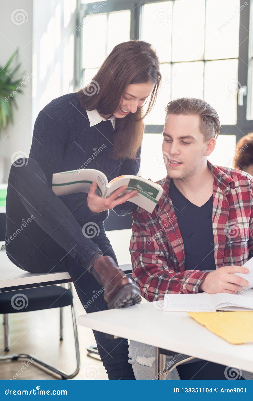 Two students checking information and knowledge while learning together. Two cheerful students checking and comparing information and knowledge while learning together in the classroom at college or university