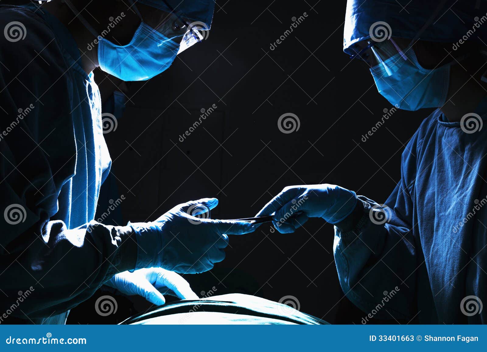 two surgeons working and passing surgical equipment in the operating room, dark