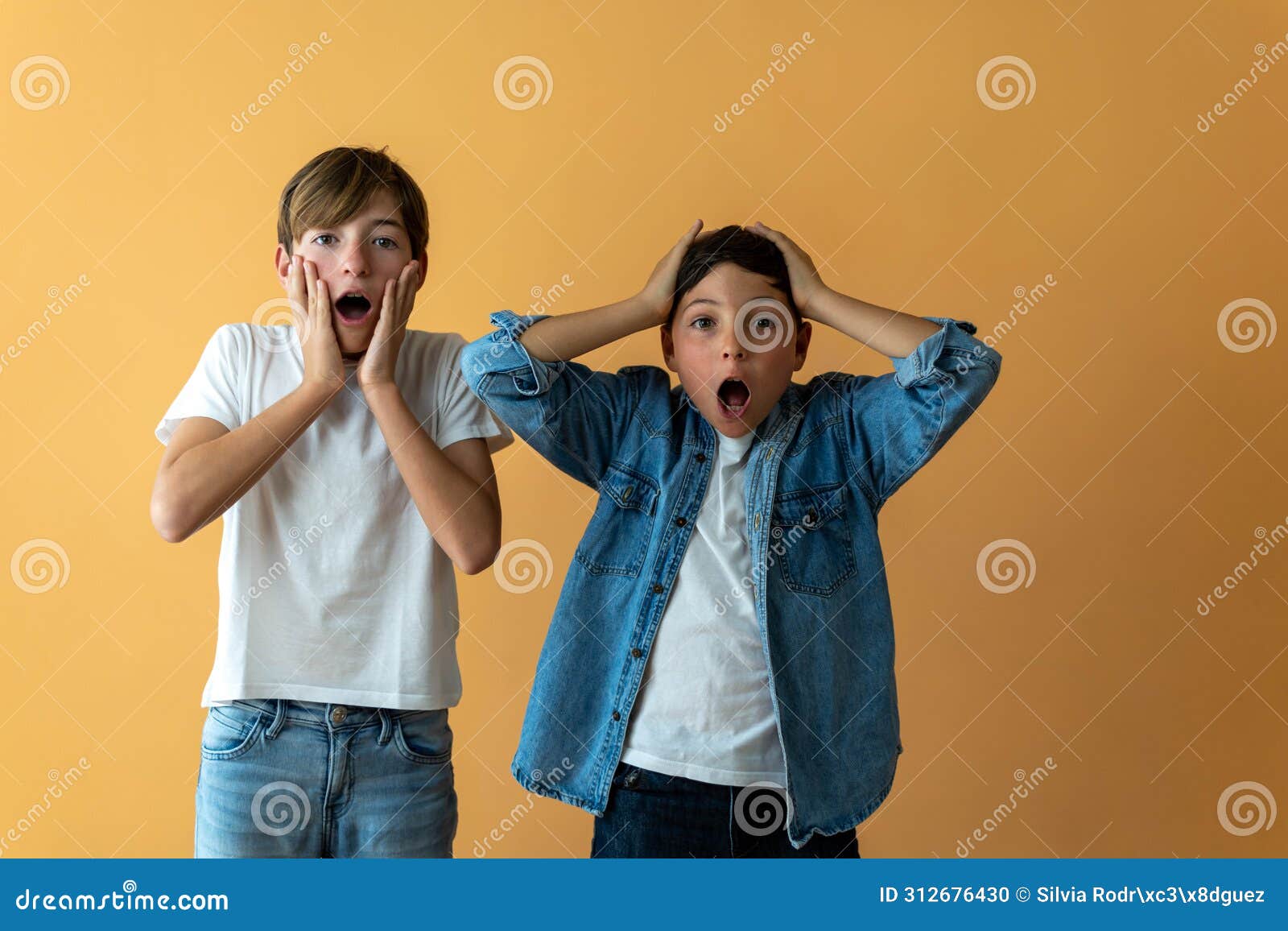 Two surprised children with their hands on their faces.