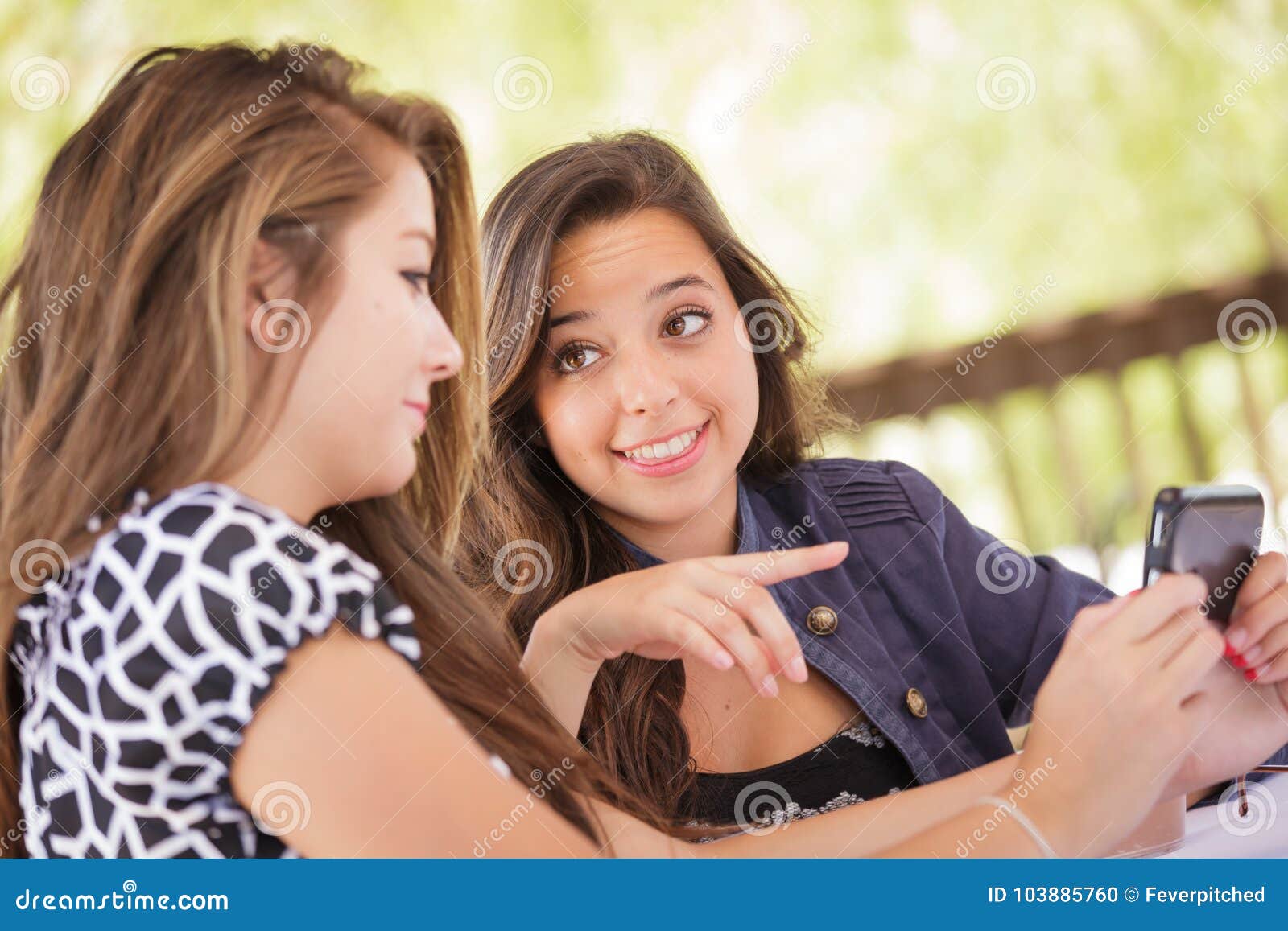 Two Teen Girlfriends Text on Their Smart Phone Stoc