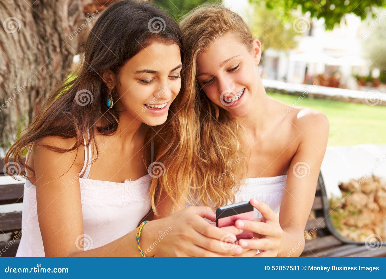 Two Teenage Girls Using Mobile Phone Sitting on Park Bench Stock Image ...