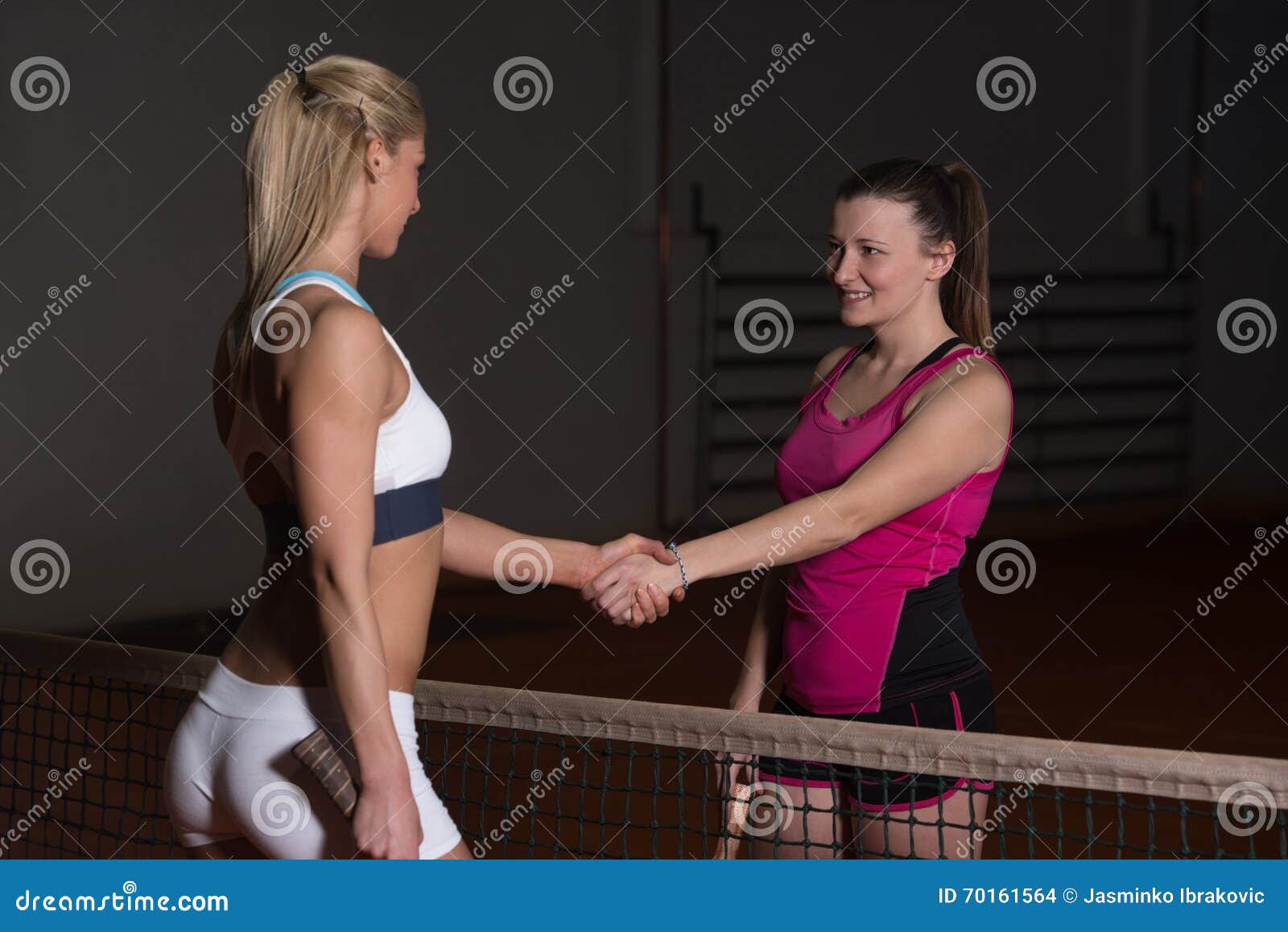two tennis players shaking hands over the net