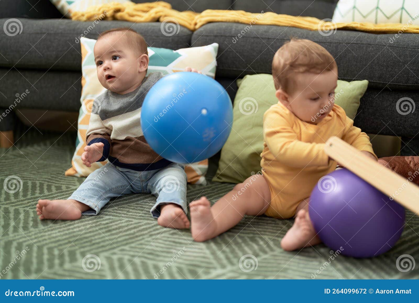 Two Toddlers Playing with Balls Sitting on Floor at Home Stock Photo