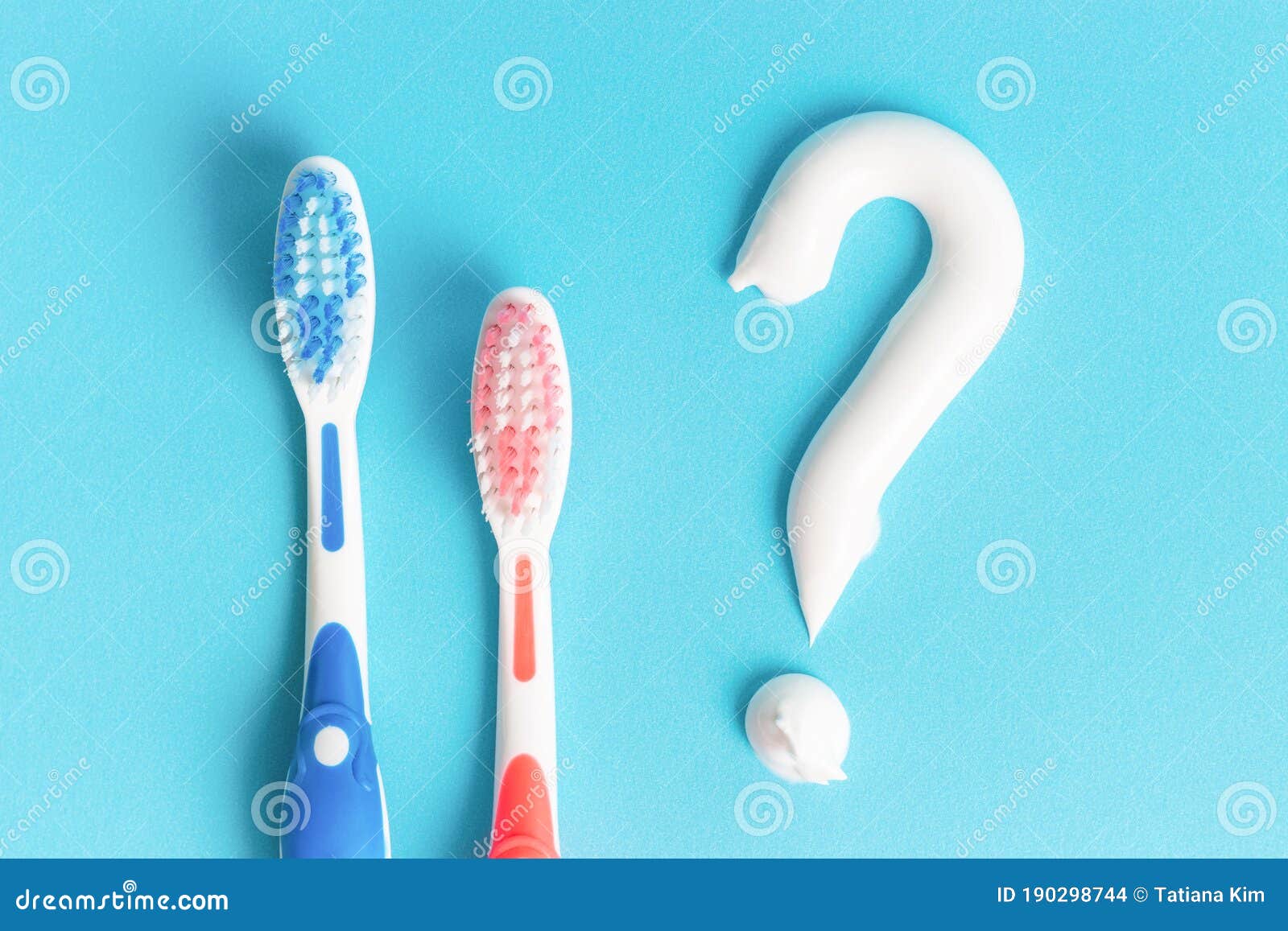 Two Toothbrushes and a Question Mark Lined with Toothpaste on Blue Background Stock Photo