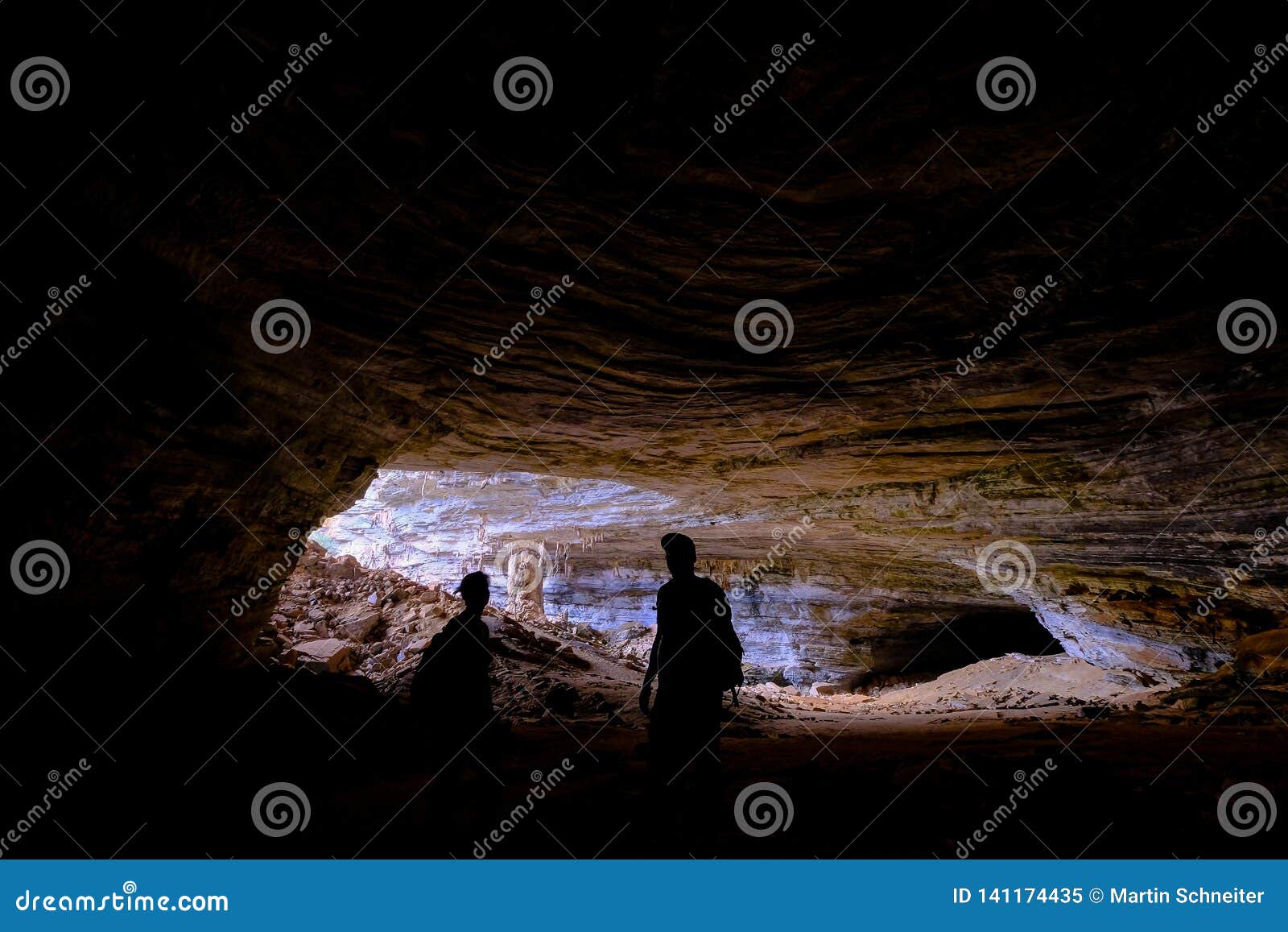 two unrecognizable tourists at the entrance of gruta da lapa doce, cave in iraquara, chapada diamantina, bahia, brazil