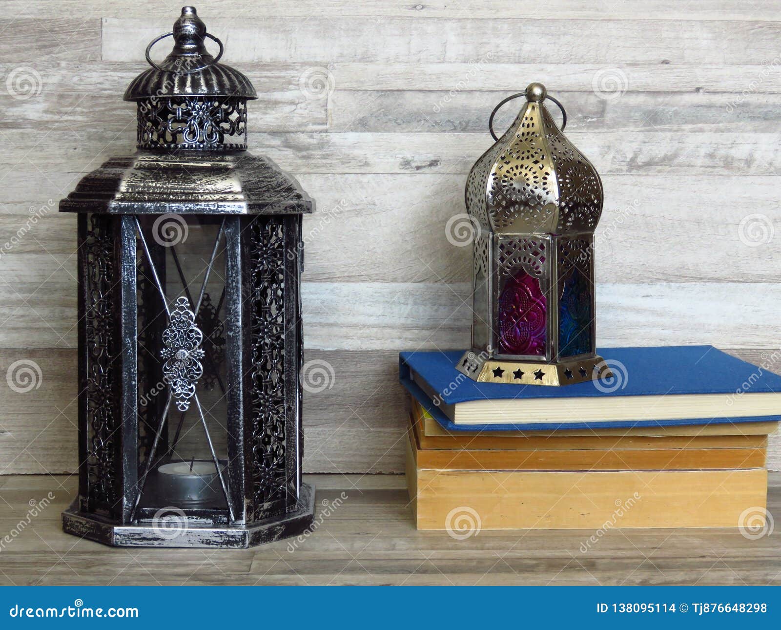 two very old silver lanterns and a pile of old books on bleached oak background.