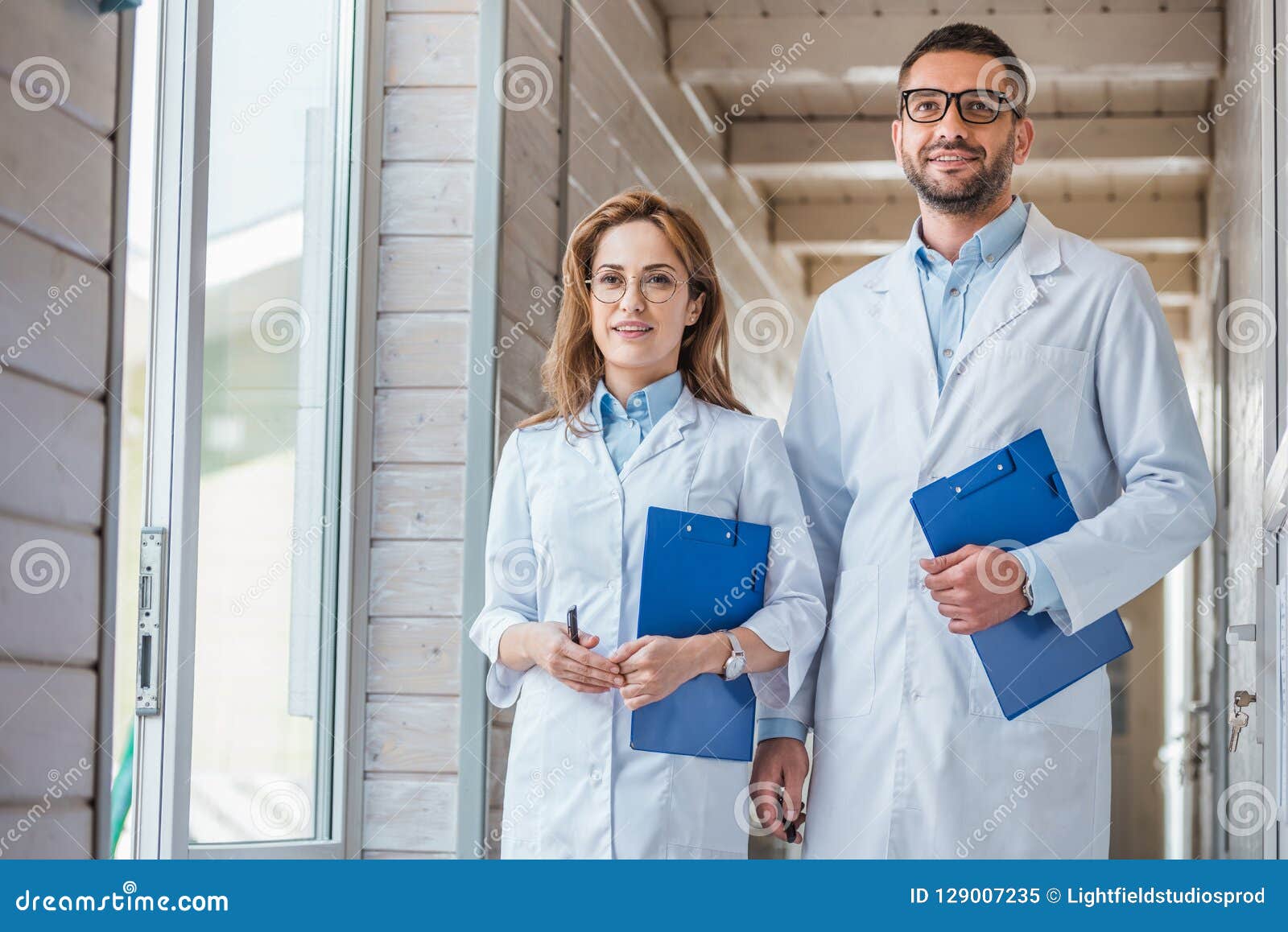 two veterinarians in white coats walking with clipboards in veterinary