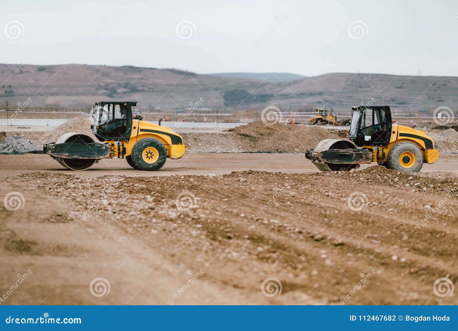 two vibratory soil compactors during road and highway construction. industrial roadworks with heavy-duty machinery in construction