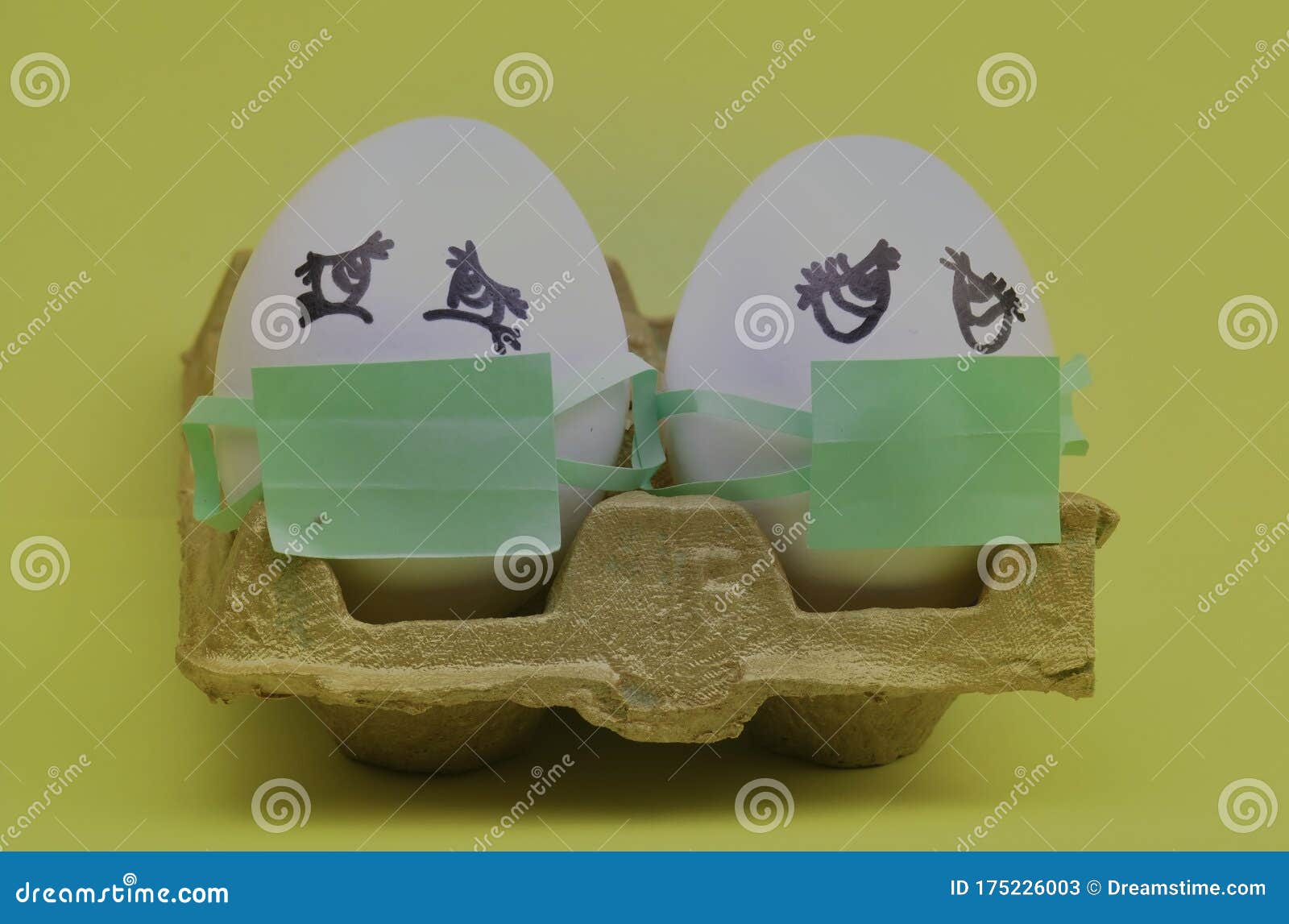 .two white eggs with green masks for fear of contagion of the coronavirus