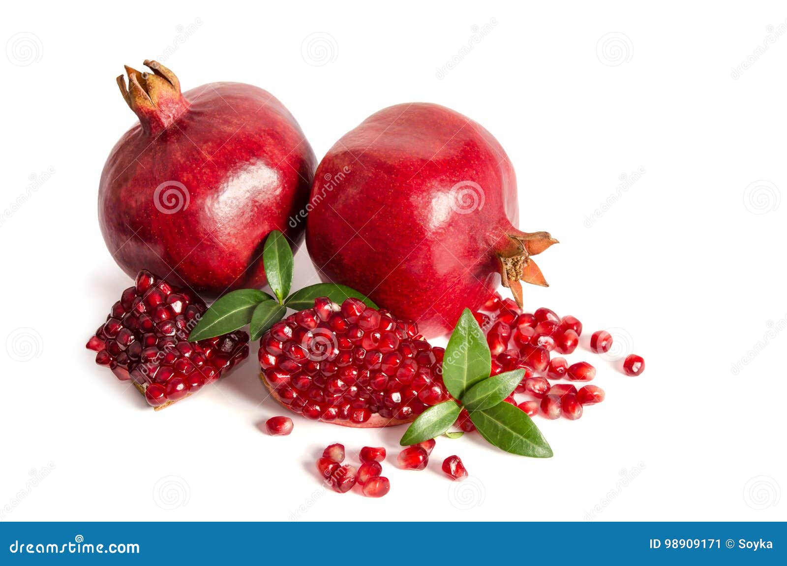 two whole and part of a pomegranate with pomegranate seeds