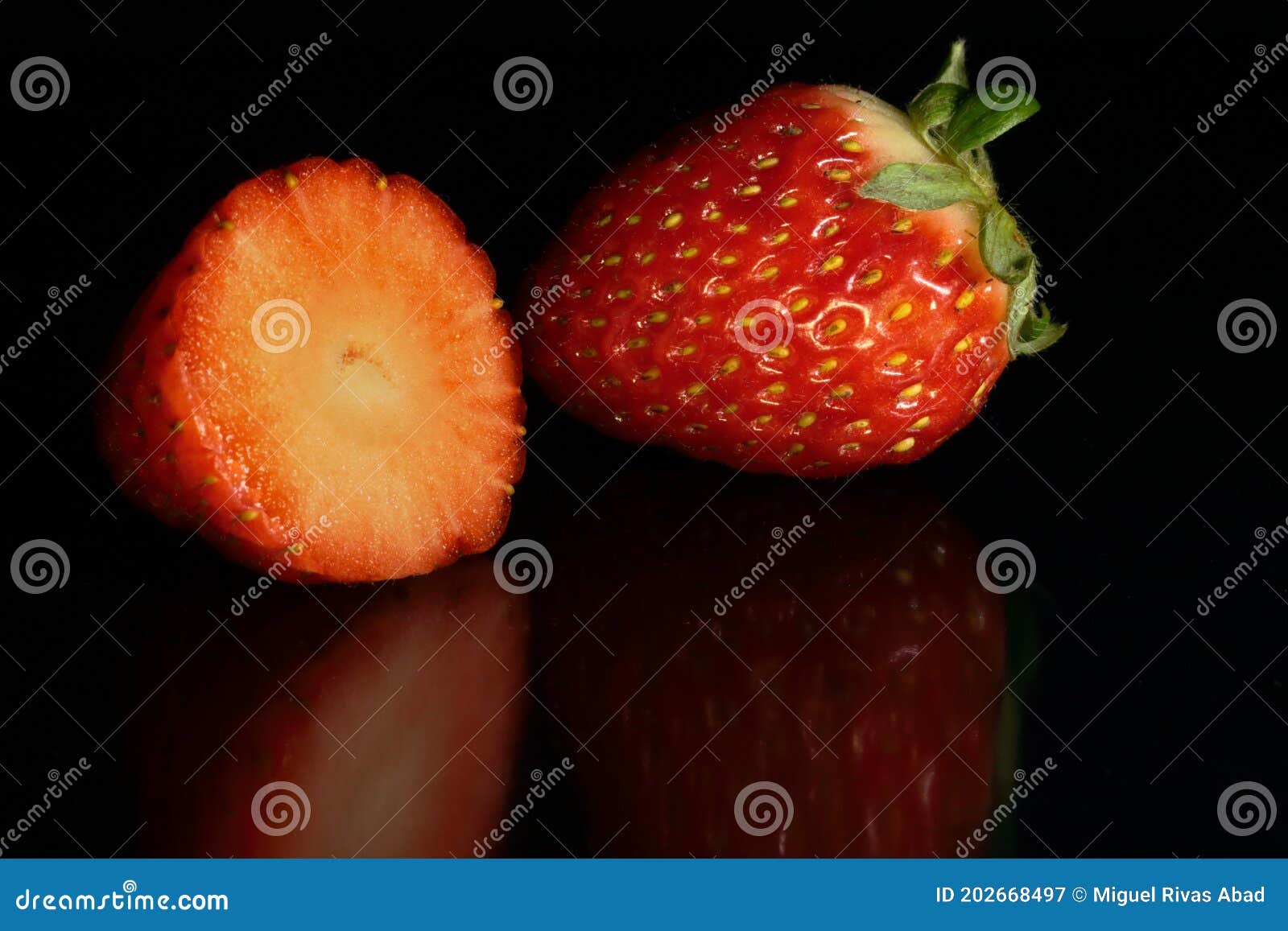 two whole and split strawberries on black background