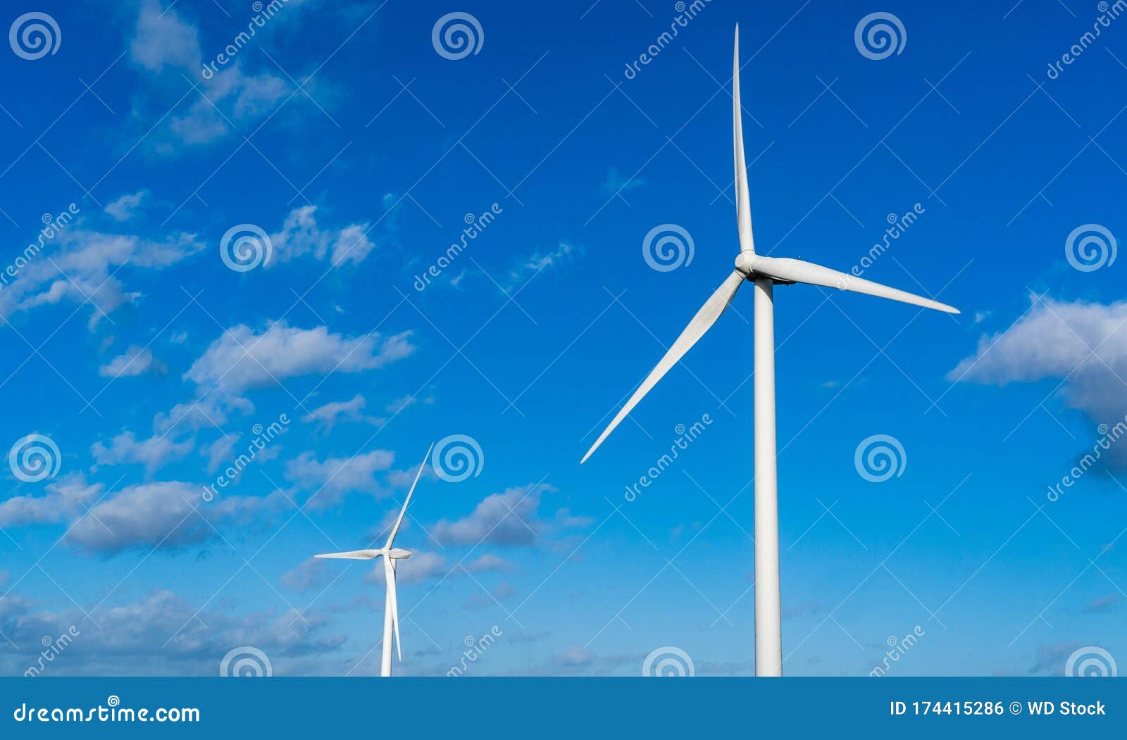two wind turbines set against a blue sky
