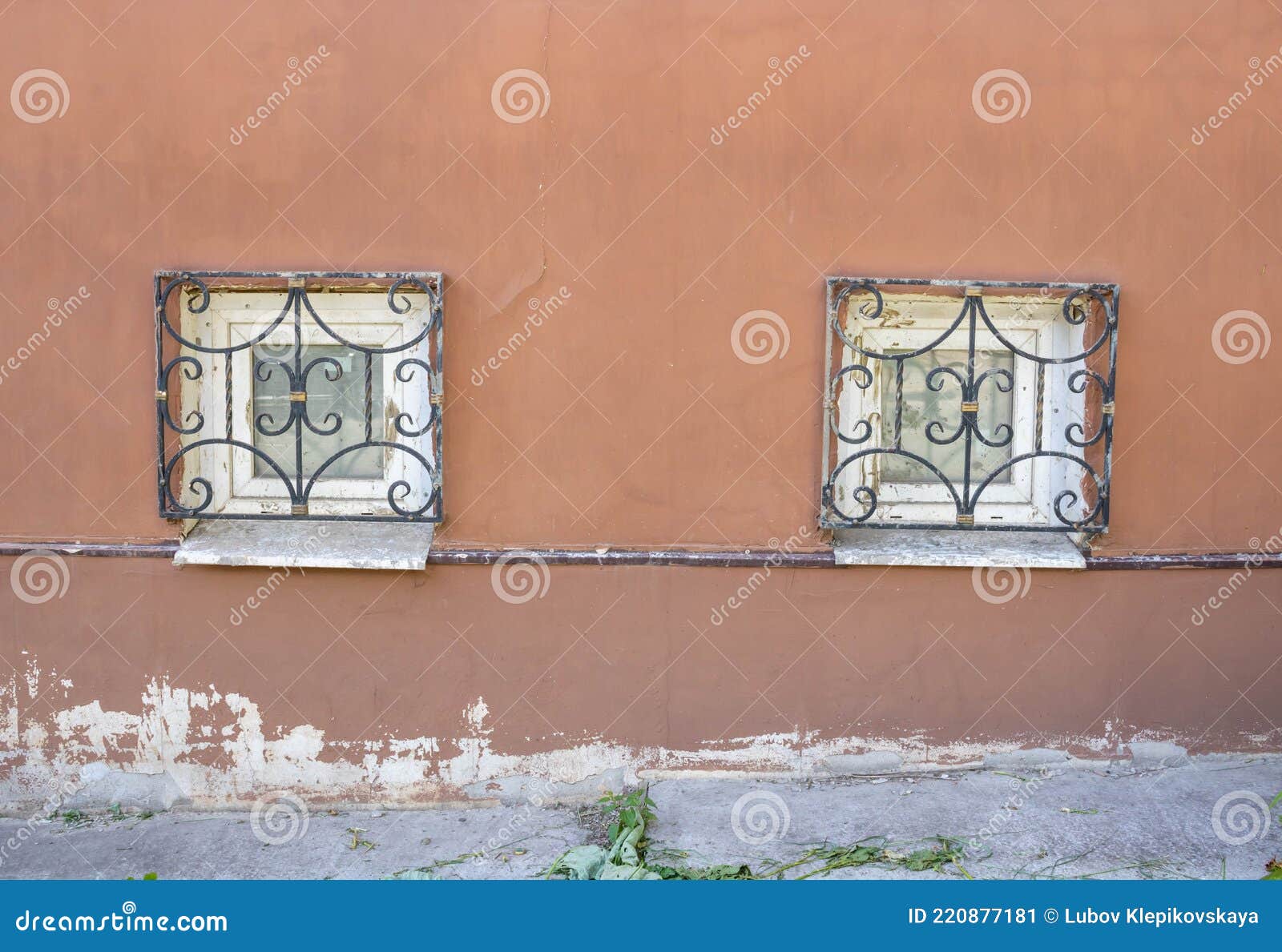 Two Windows with Antique Bars on the Plinth .Red Facade with Small