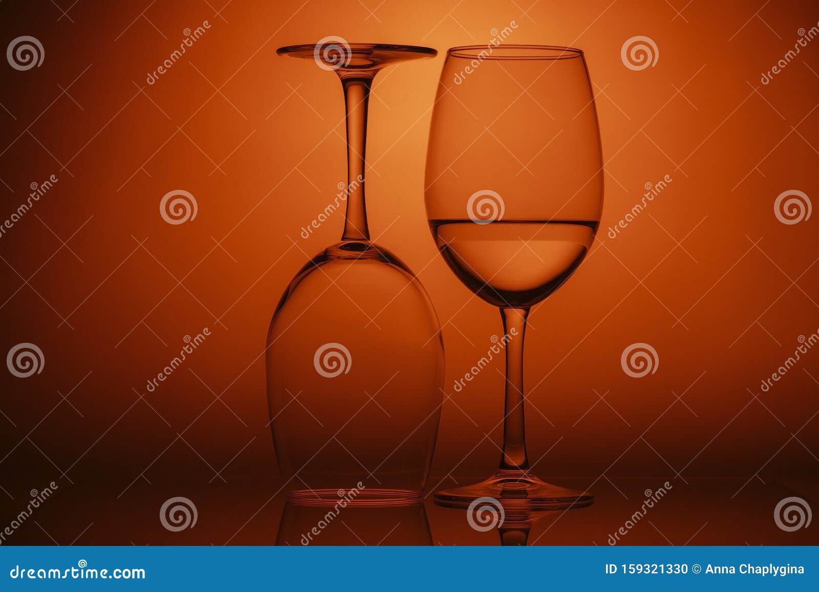 Two Wine Glasses on Orange Background. One Glass Upside Down Stock