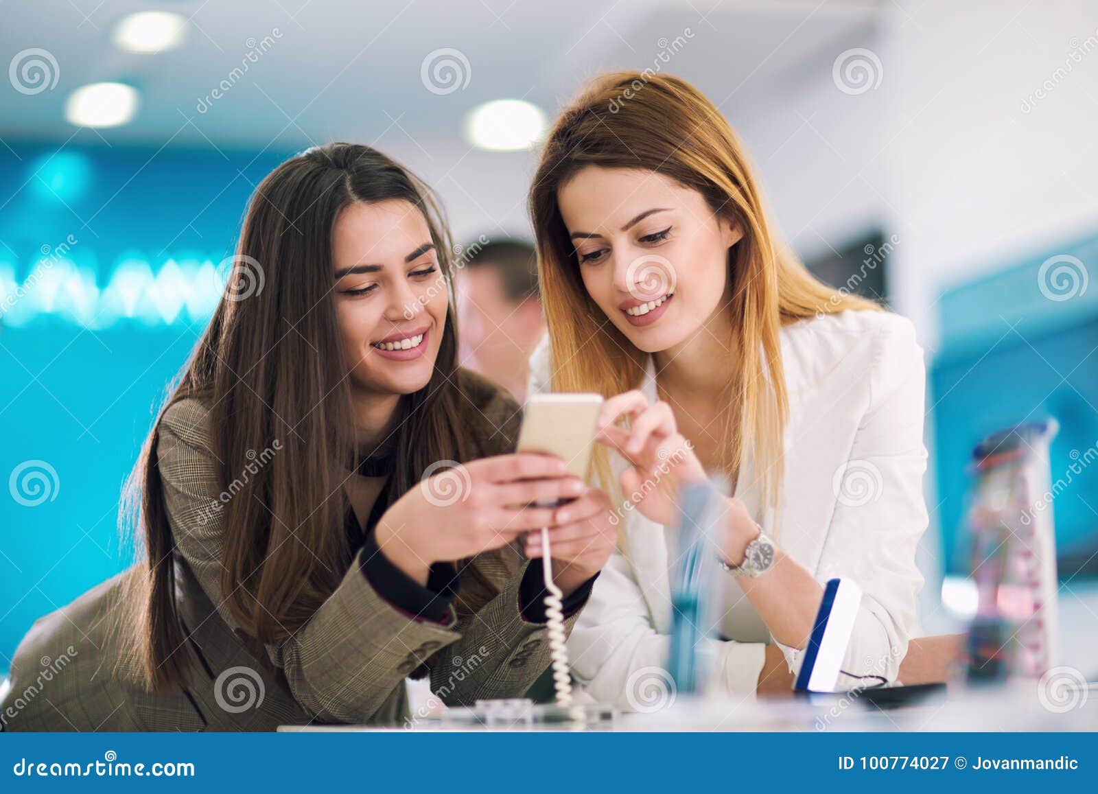 Two Women Holding a Mobile Phone in Store. Stock Image - Image of ...