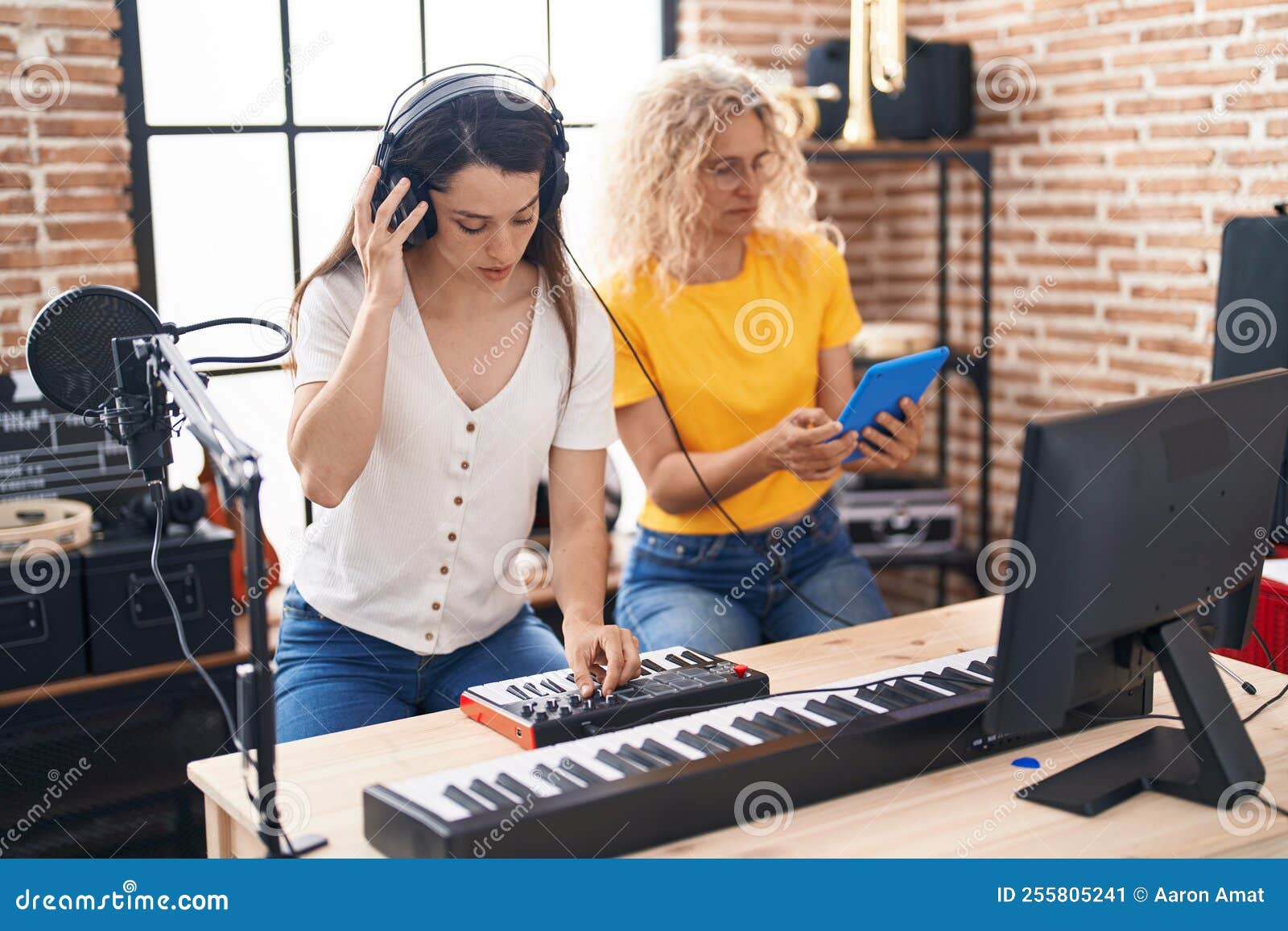 Two Women Musicians Composing Song Using Keyboard and Touchpad at Music