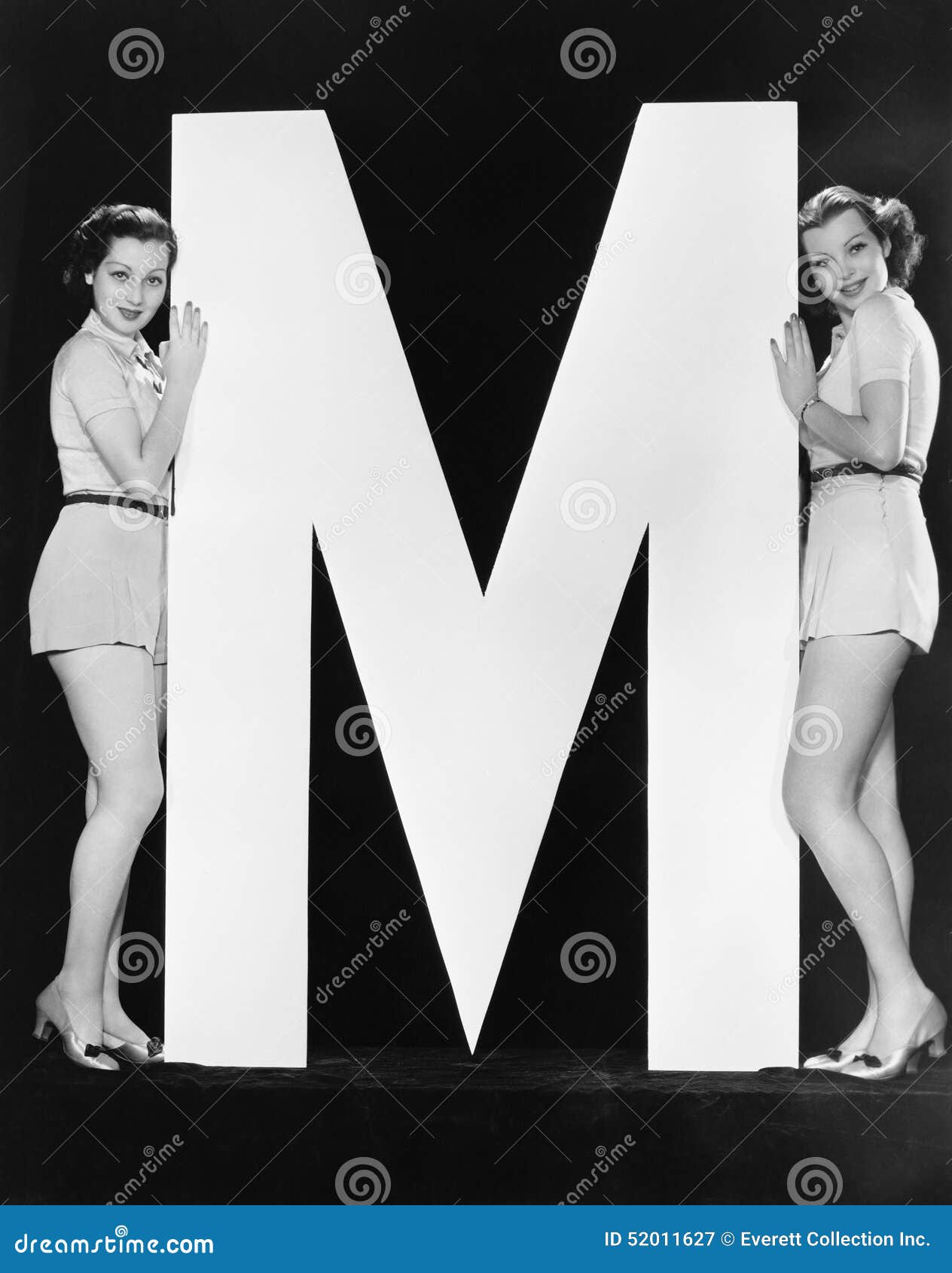 two women posing with huge letter m