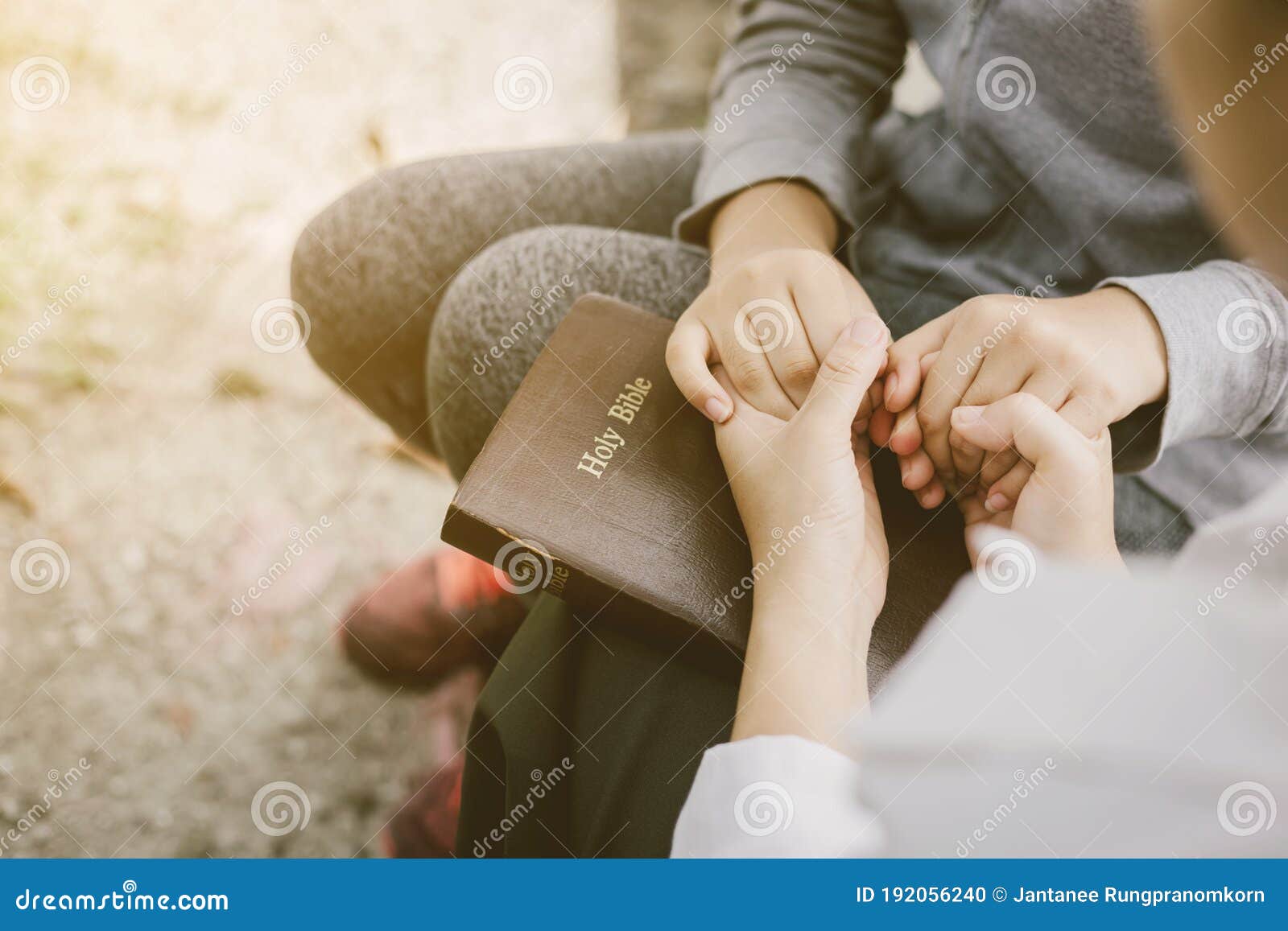two women pray on the bible