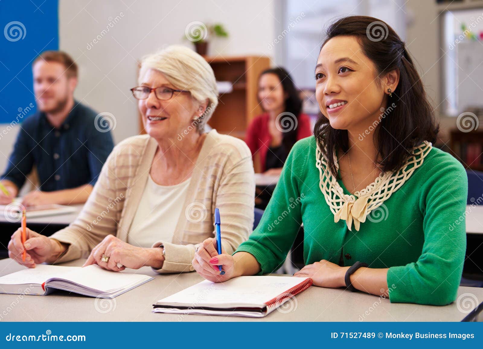 two women sharing a desk at an adult education class look up