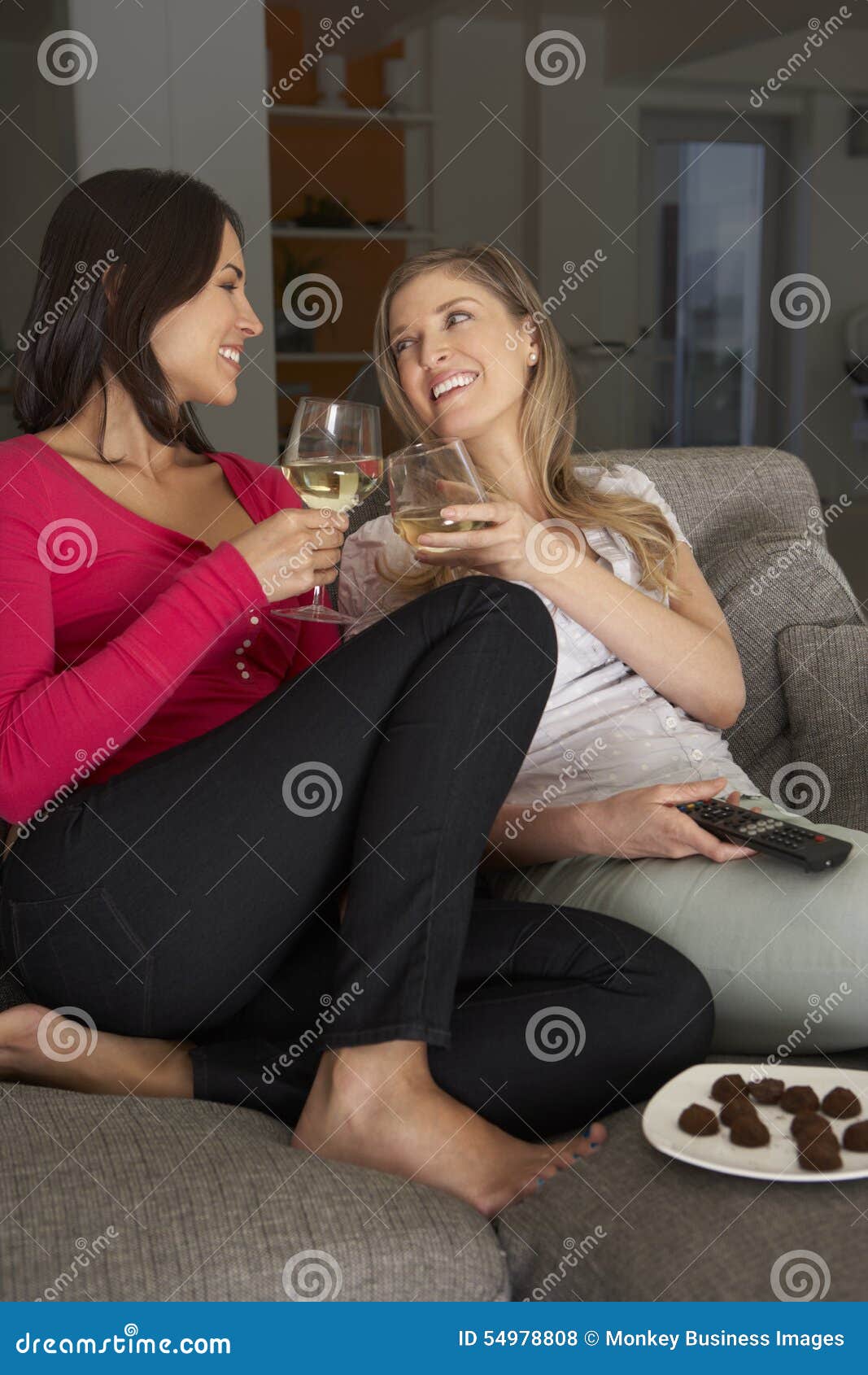 Two Women Sitting on Sofa Watching TV Drinking Wine Stock Photo Image