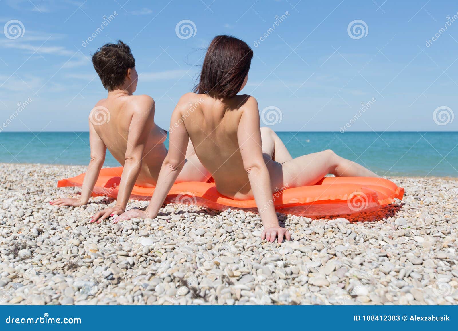 Two Women Sunbathing on Pebble Beach Stock Image