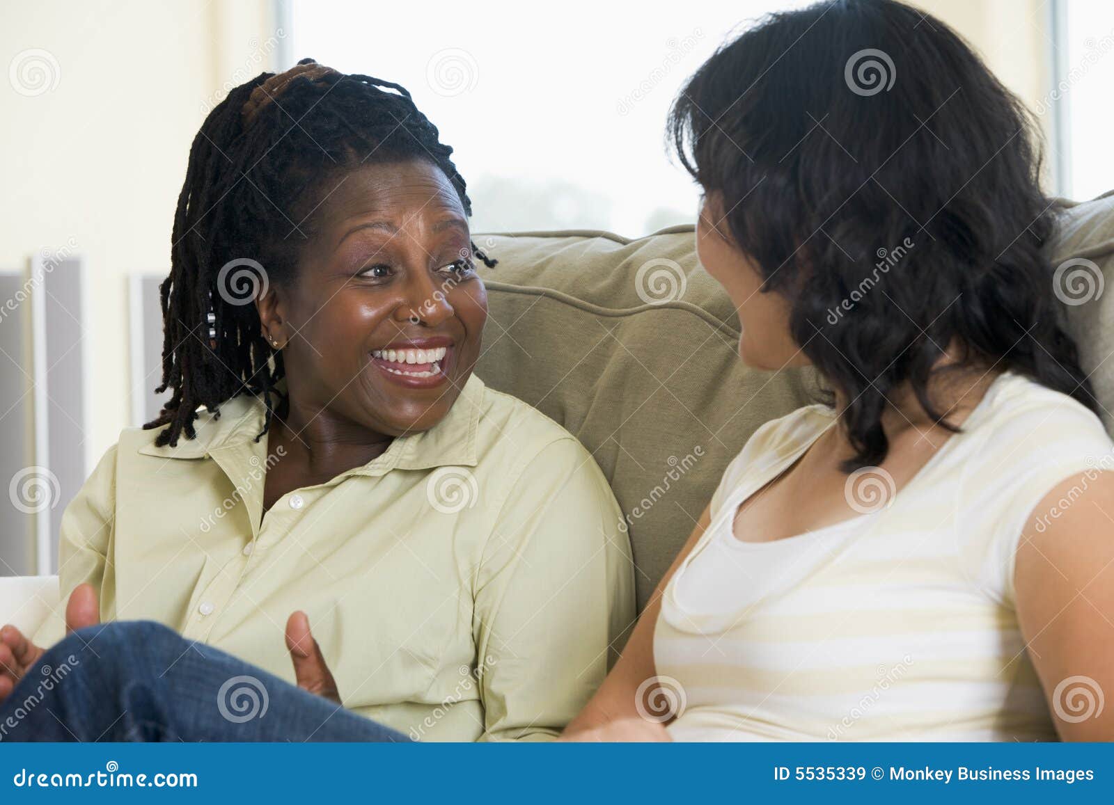 two women talking in living room and smiling