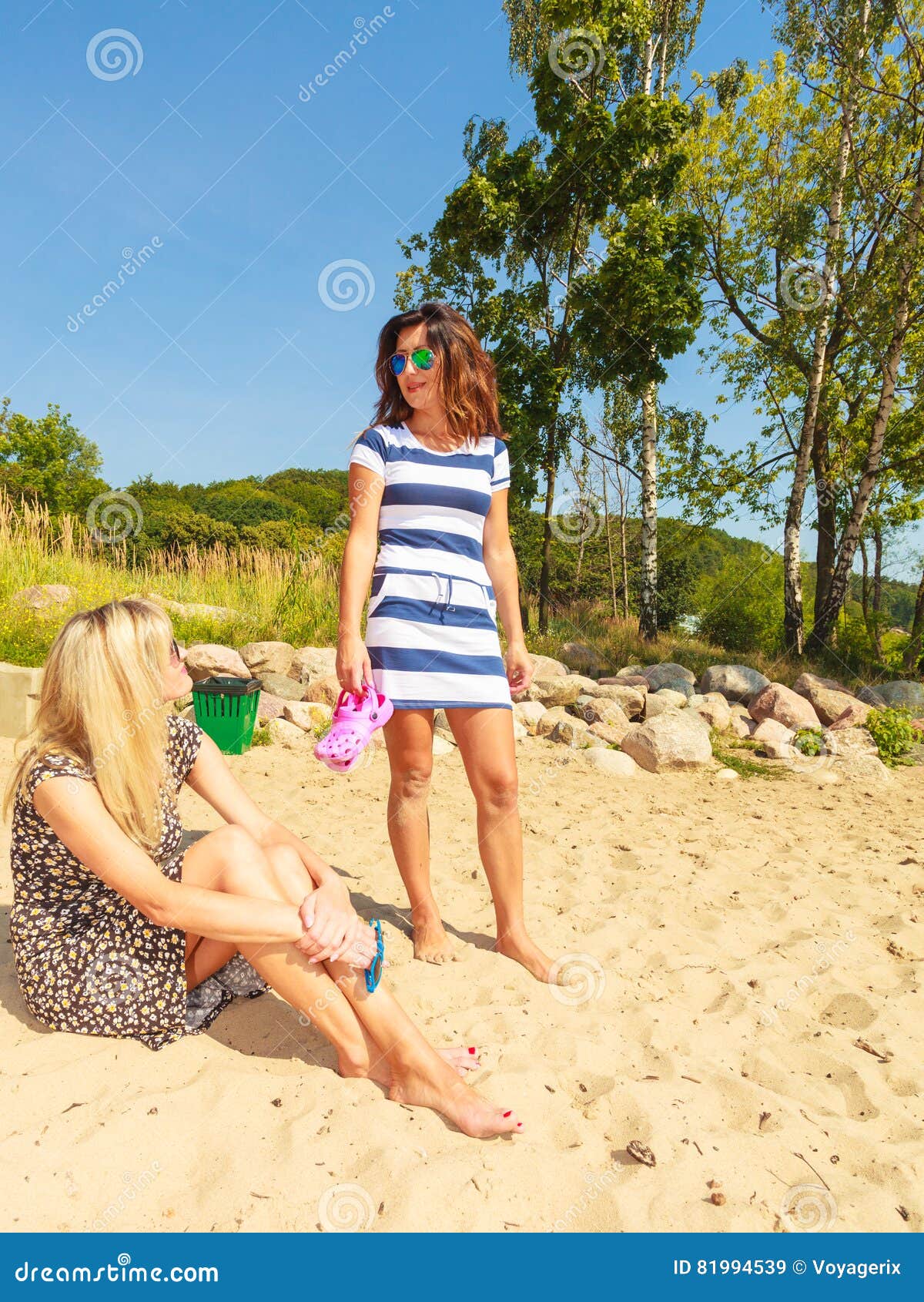 Two alluring women are relaxing on the nudist beach