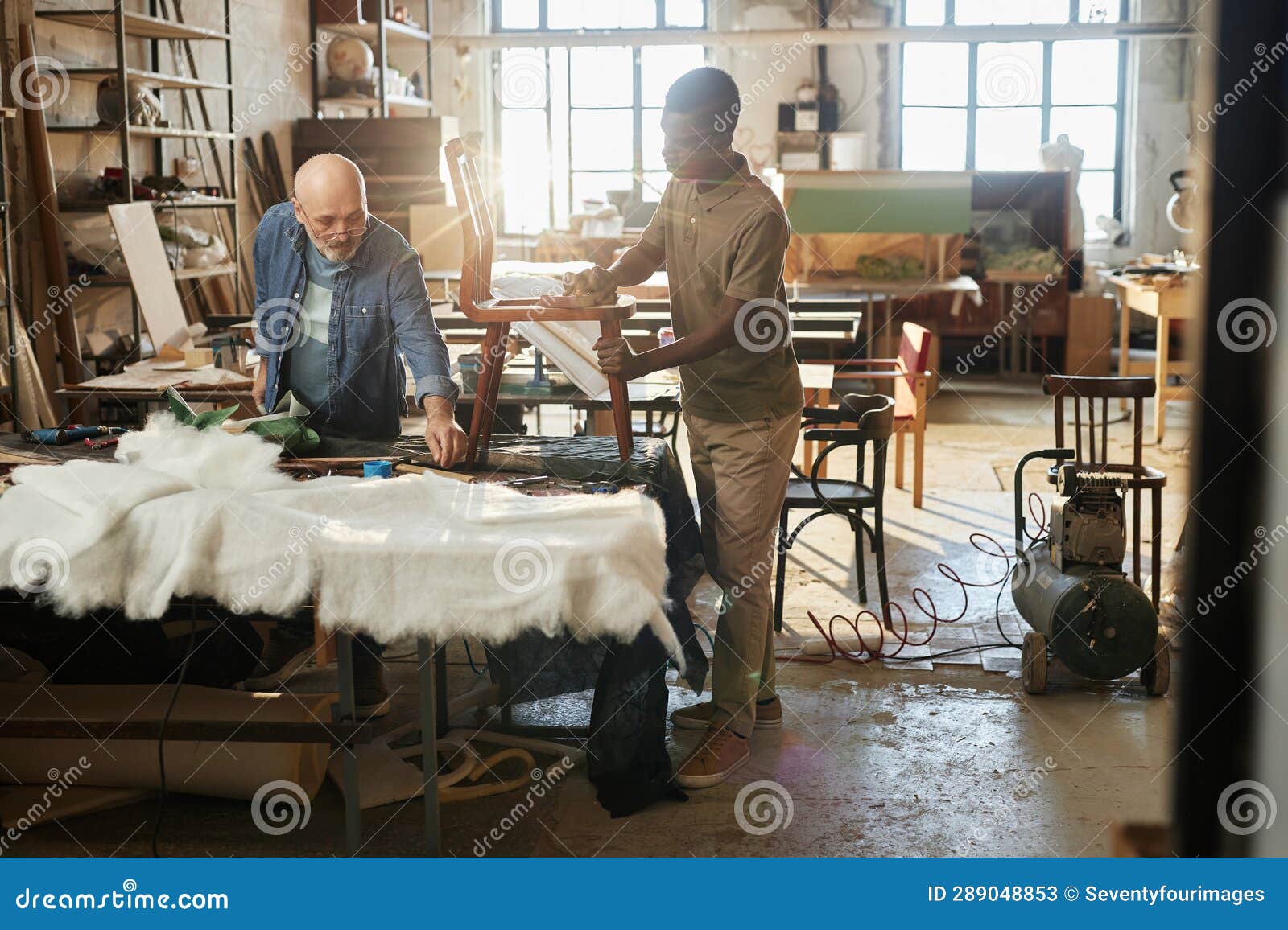 two workers refurbishing furniture in workshop