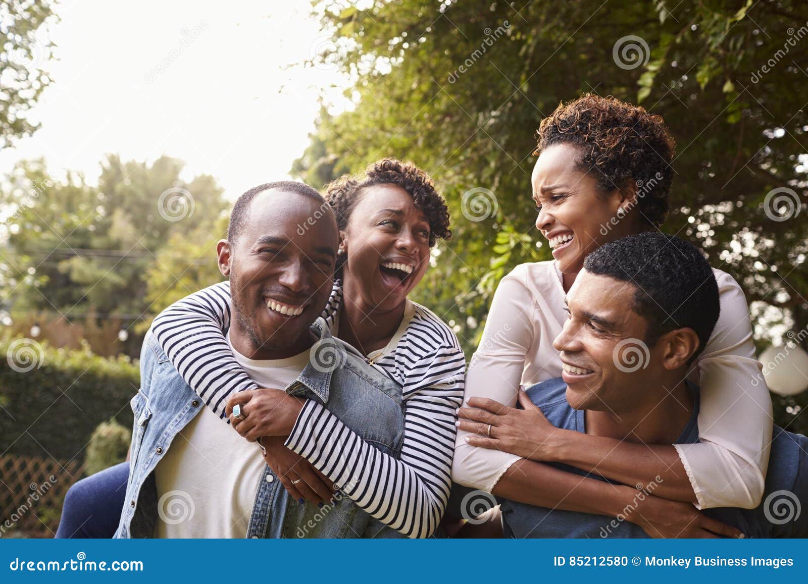 two young adult black couples having fun piggybacking