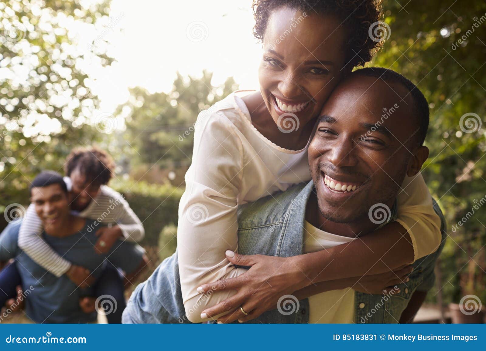 two young adult black couples piggybacking look to camera