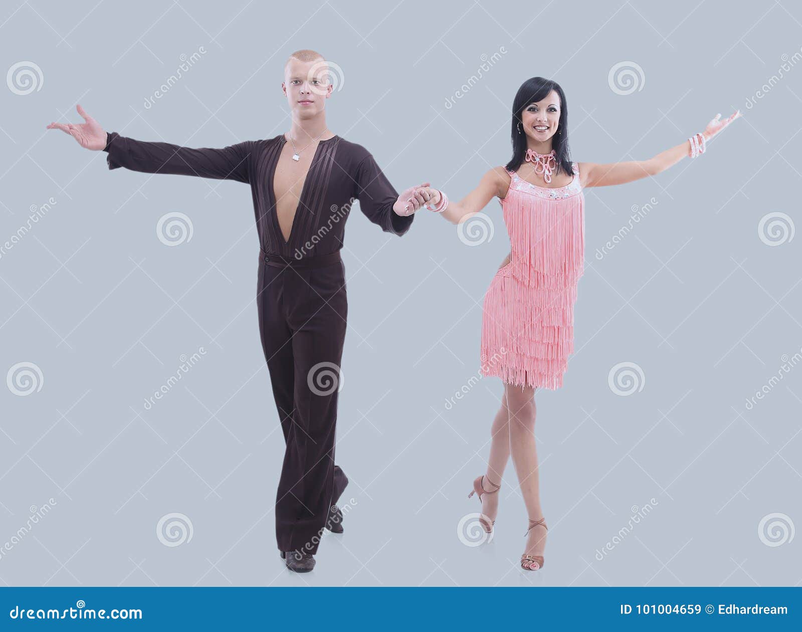 Two Young Ballroom Dancers In Studio Against Gray Background