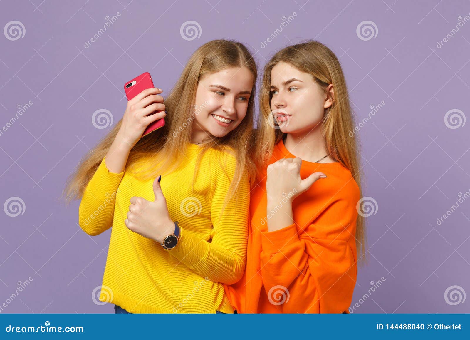 Two Young Blonde Twins Sisters Girls in Vivid Clothes Pointing Thumb ...
