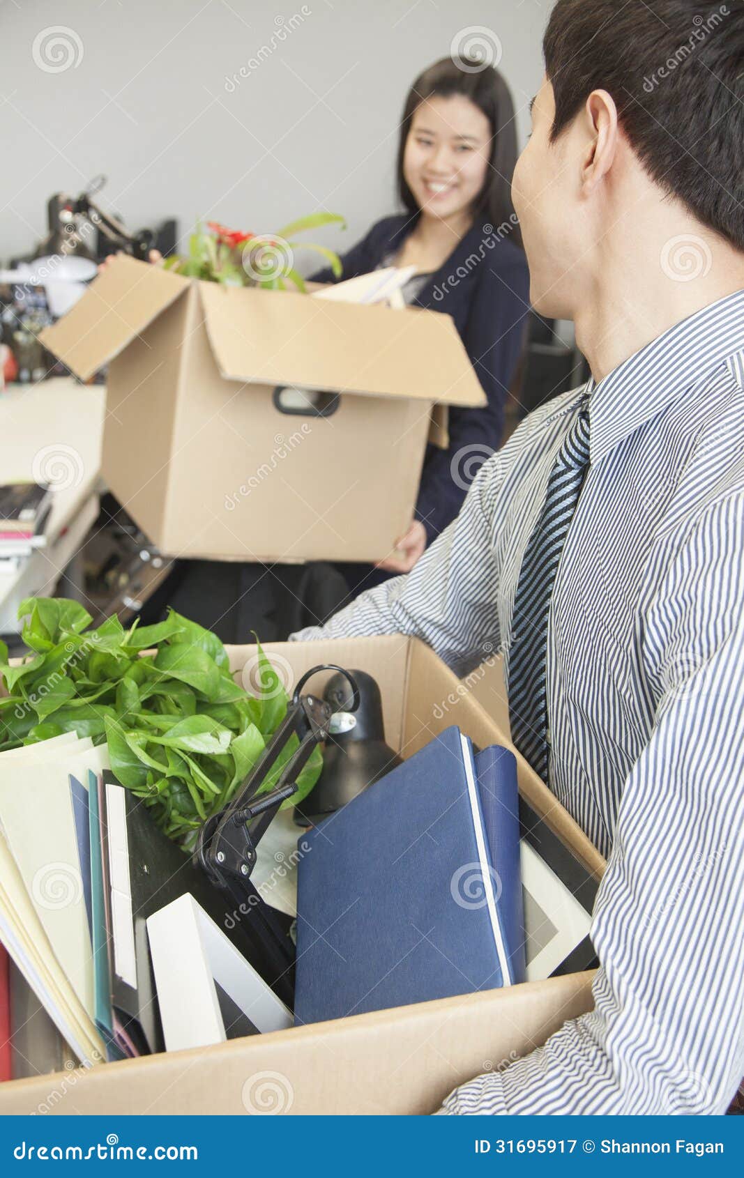 Two Young Business People Carrying Boxes with Office Items Stock Image