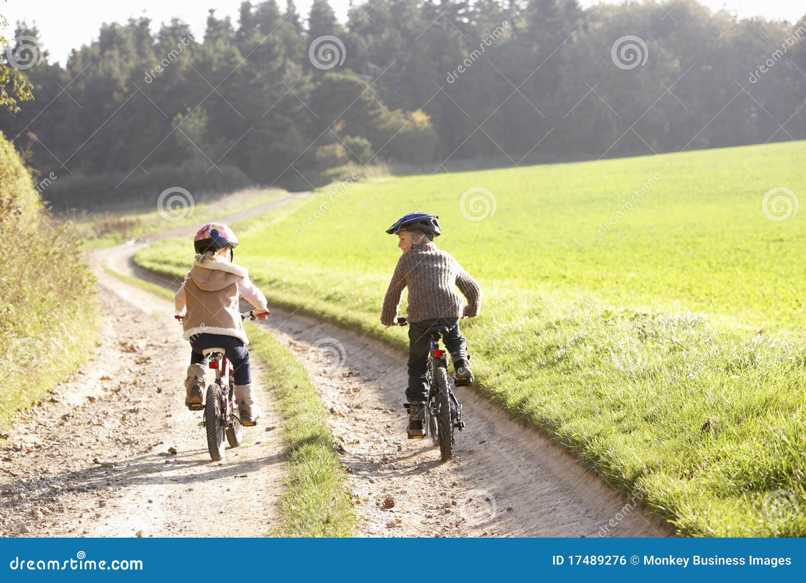 two young children ride bicycles in park
