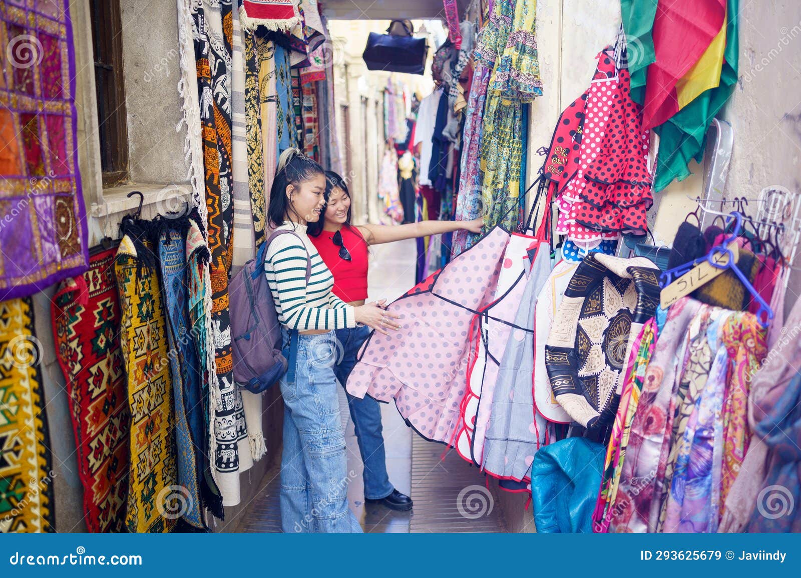 two young chinese women looking at typical clothes in the typical handicraft