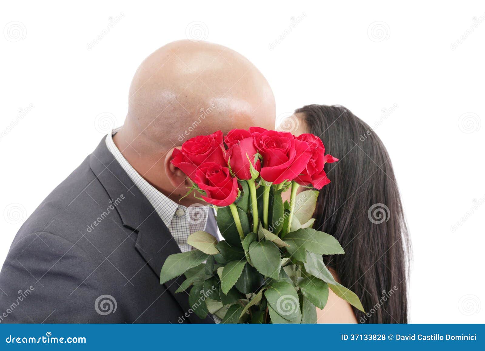 Two Young Dates Kissing Behind a Bouquet of Red Roses Stock Photo