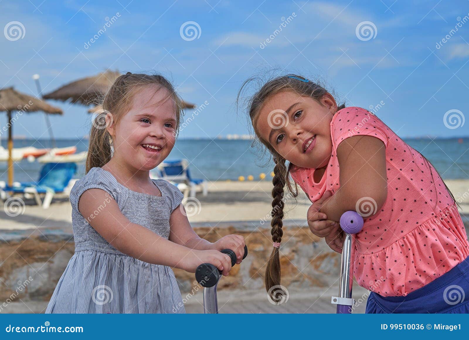 two happy young girls on scooters by the beach