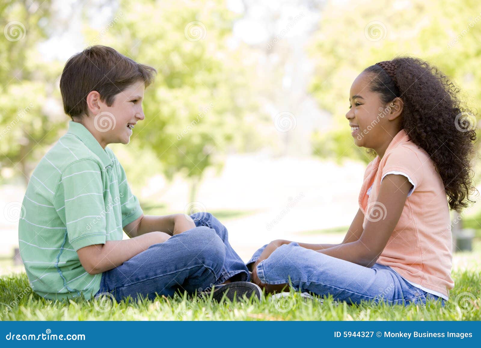 two young friends sitting outdoors looking at each