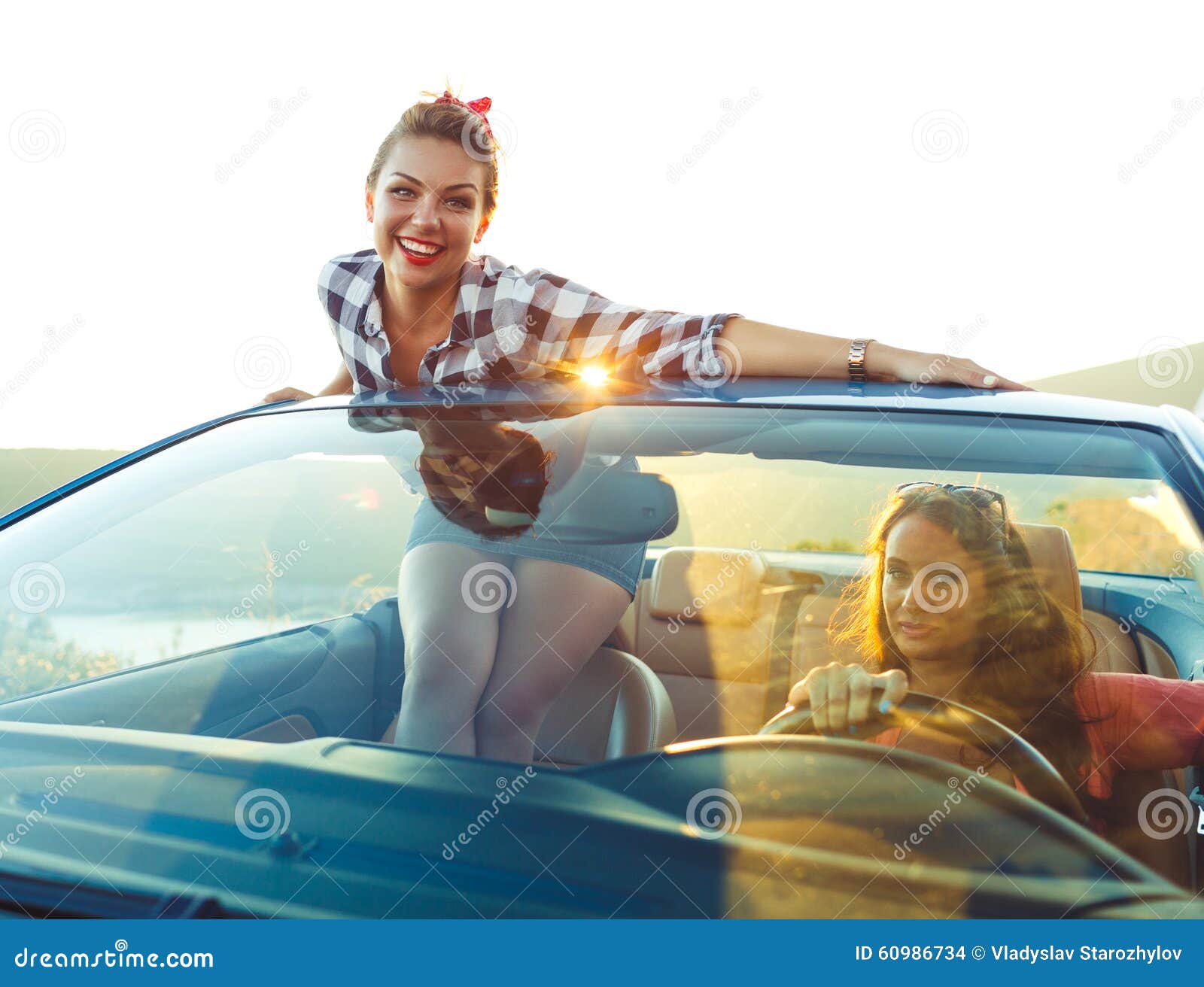 Two young happy girls driving a cabriolet