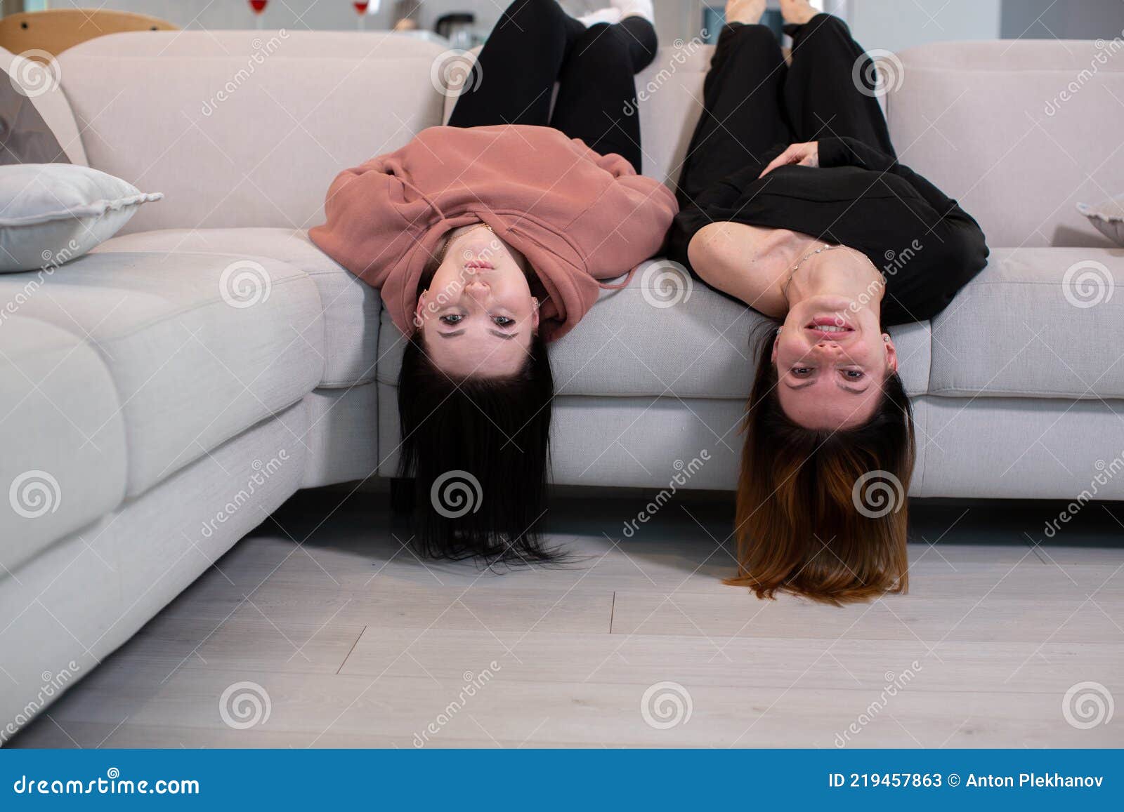 Two Young Girls Lie On The Couch With Their Legs Up Staring At The Camera Stock Image Image