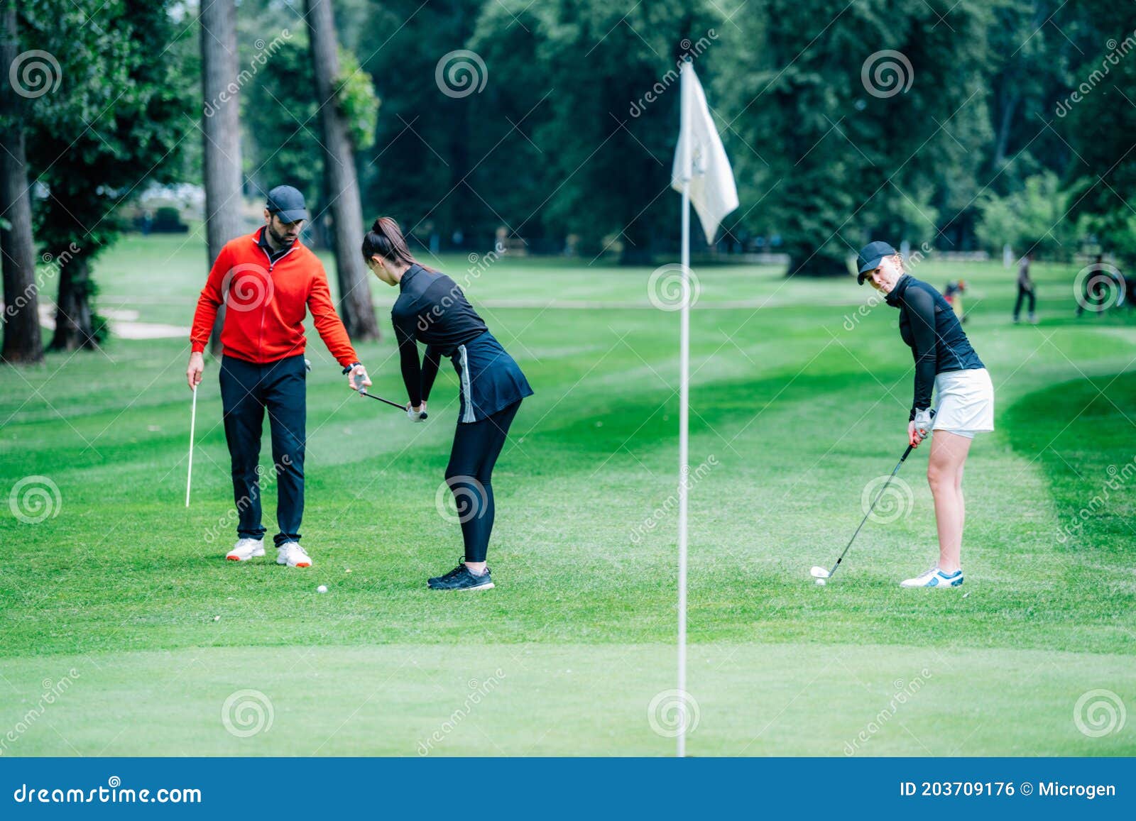 Two Young Golfers Practicing Chipping Shots on a Golf Course with Golf