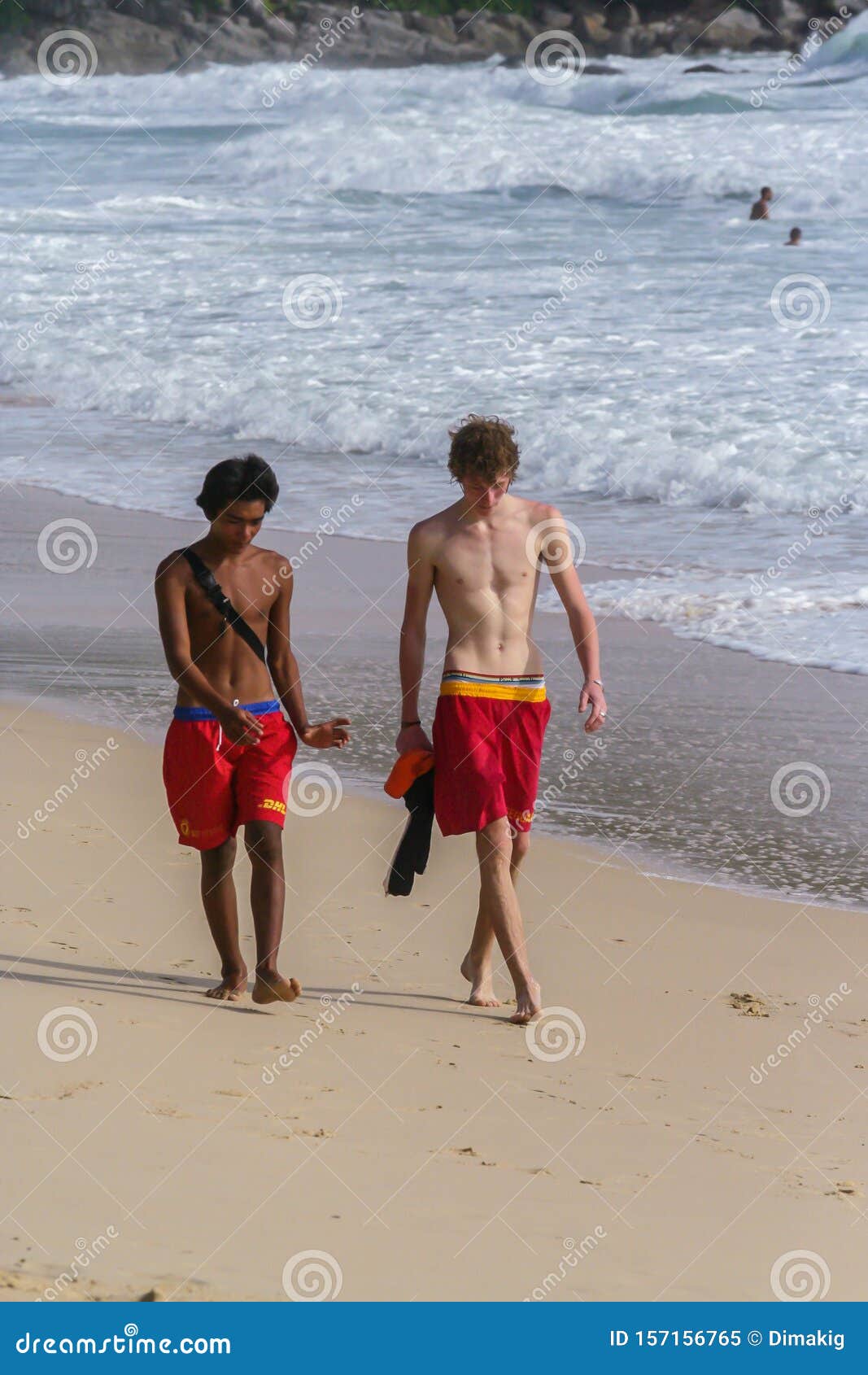 Two Young Guys Walking Along The Coastline Of Ocean Tourism Of Asia