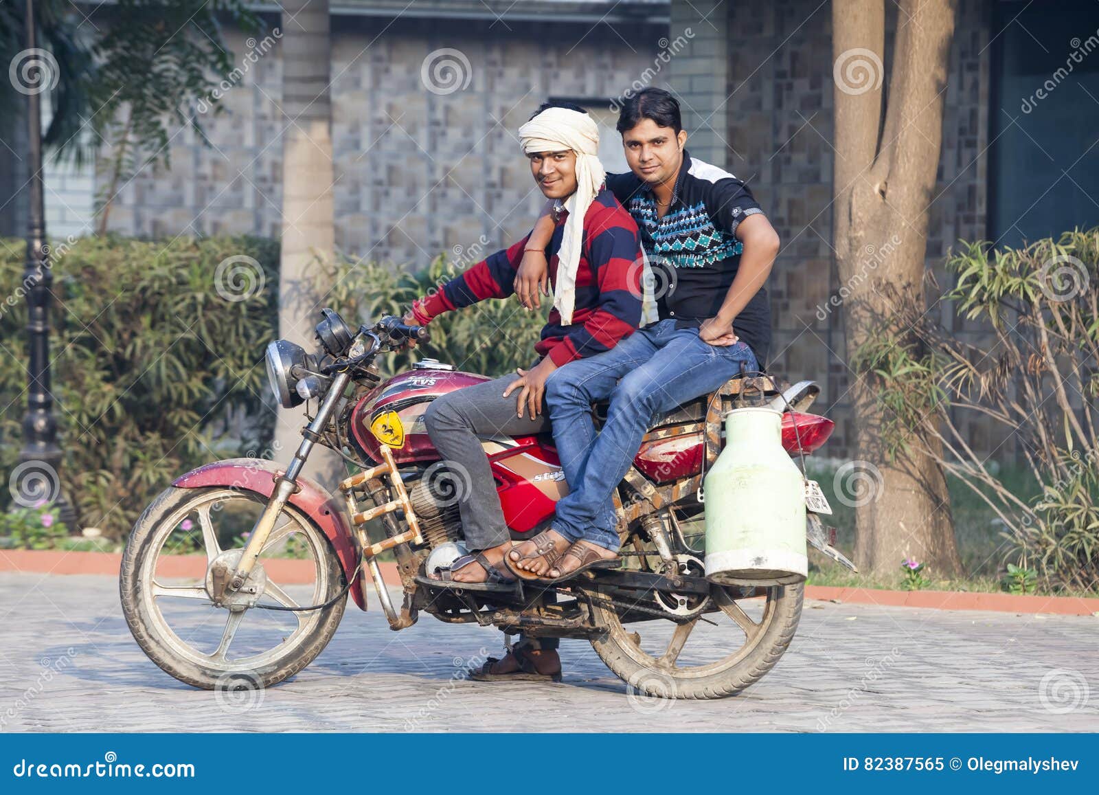 Two Young Indian Man Sit on a Motorcycle Seller of Milk from Milk Cans.India, Vrindavan