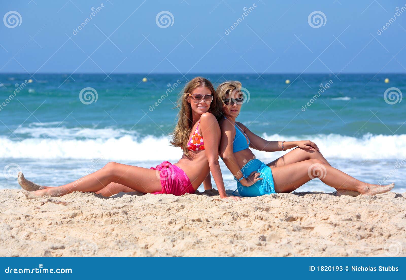 Two Young and Healthy Girls Sitting on a Sunny Beach Stock Image picture