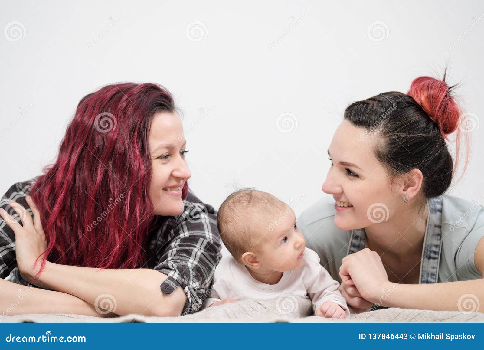 Two Young Women with a Baby on a White Background