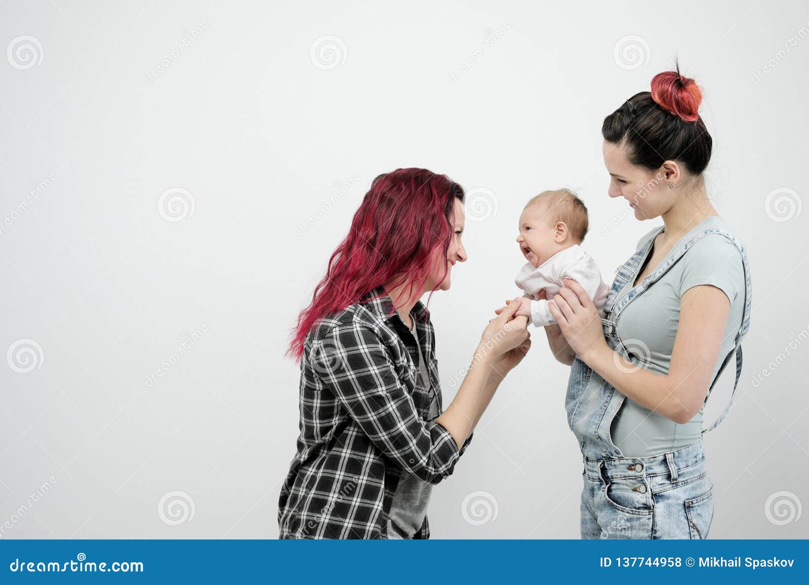 Two Young Women with a Baby on a White Background image