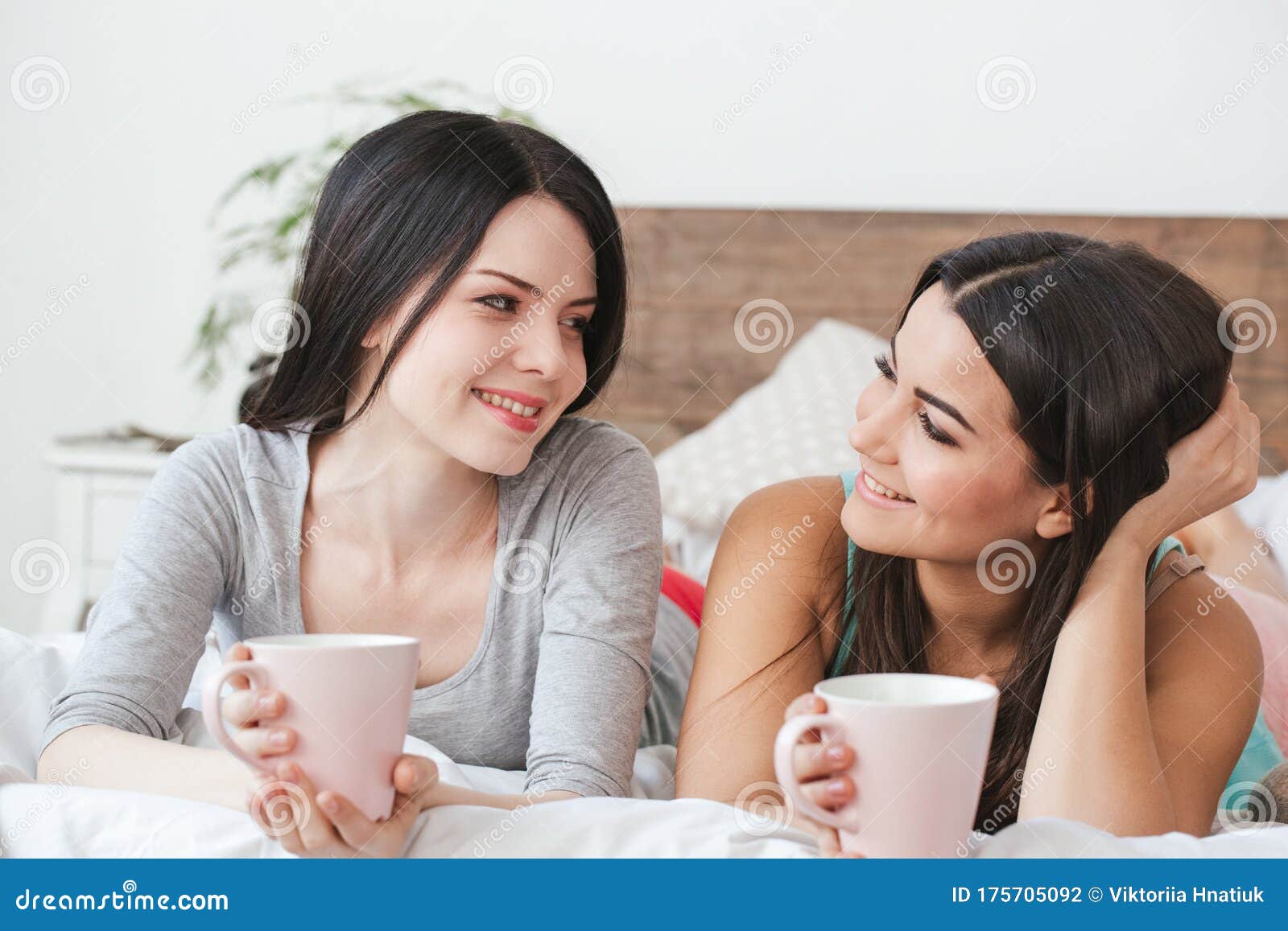 Lesbian Couple In Bedroom At Home Lying Drinking Tea