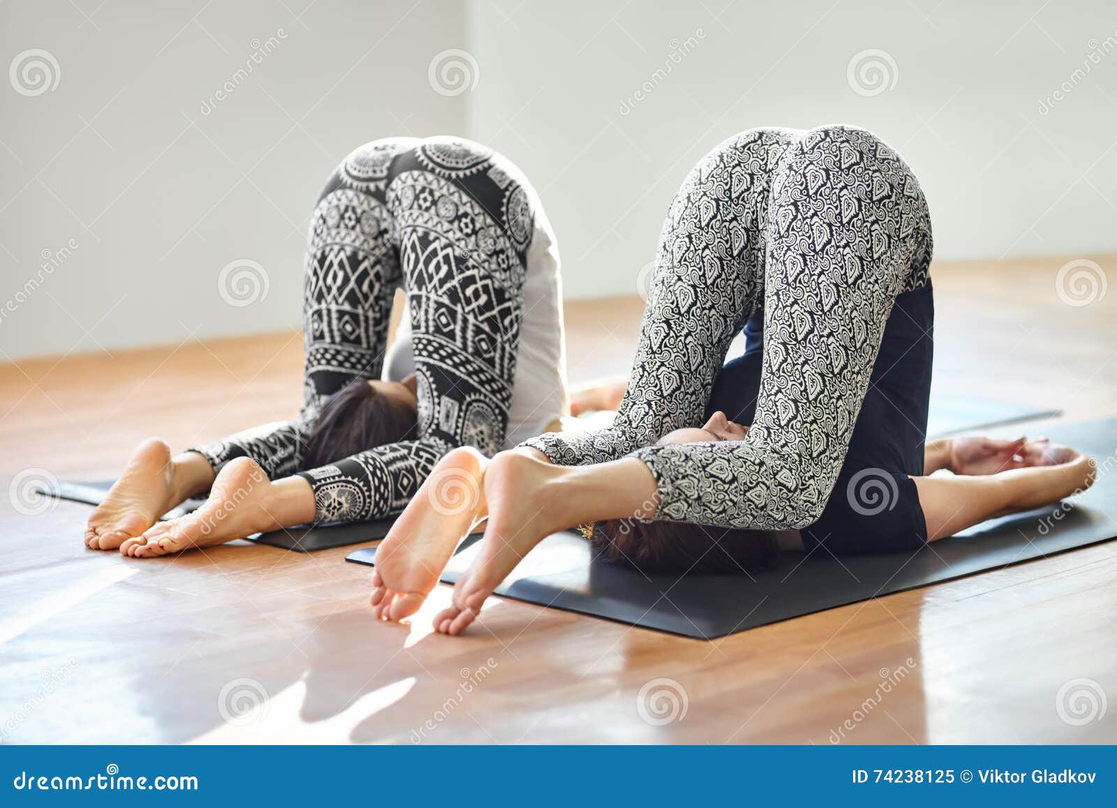 two women practicing yoga, Halasana exercise, Plough pose Stock Photo by  renatahamuda