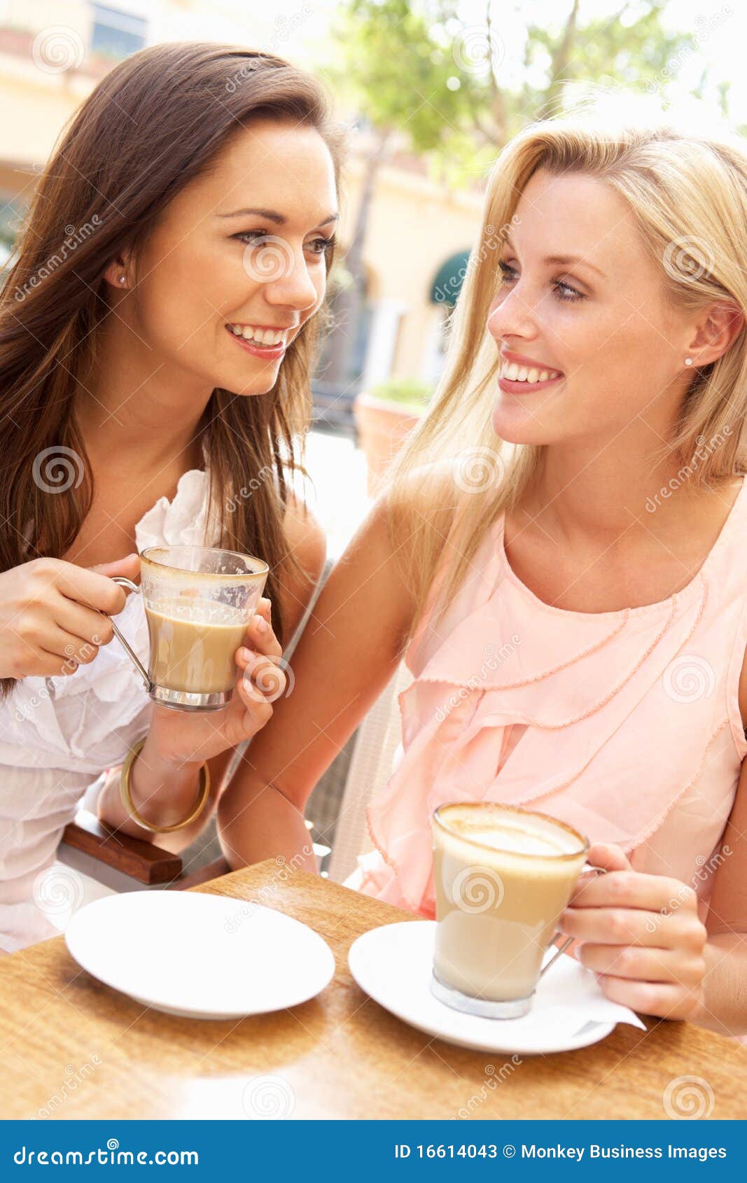 Two Young Women Enjoying Cup Of Coffee In Cafe