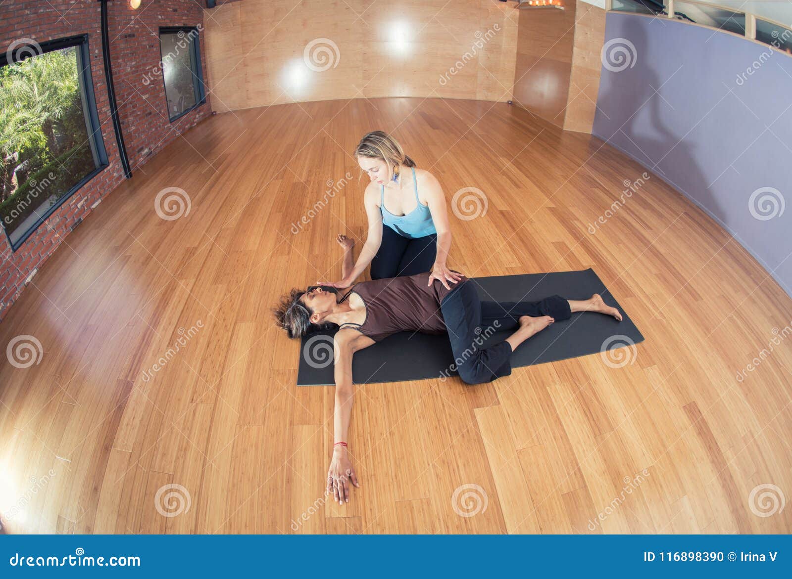 Two Young Women Practicing Yoga A Yoga Instructor And A Yoga Practitioner In A Beautiful Yoga